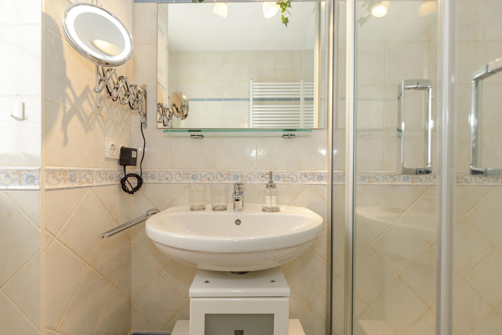 Badezimmer mit Waschbecken, Spiegel und Dusche.