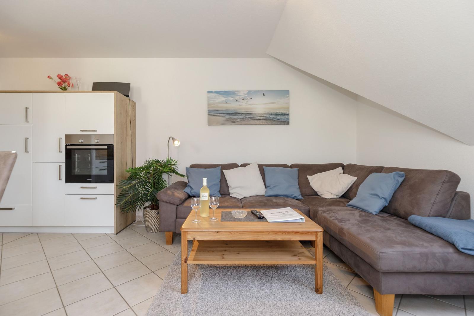 Wohnbereich mit Sofa, Couchtisch und Küchenzeile unter Dachschräge