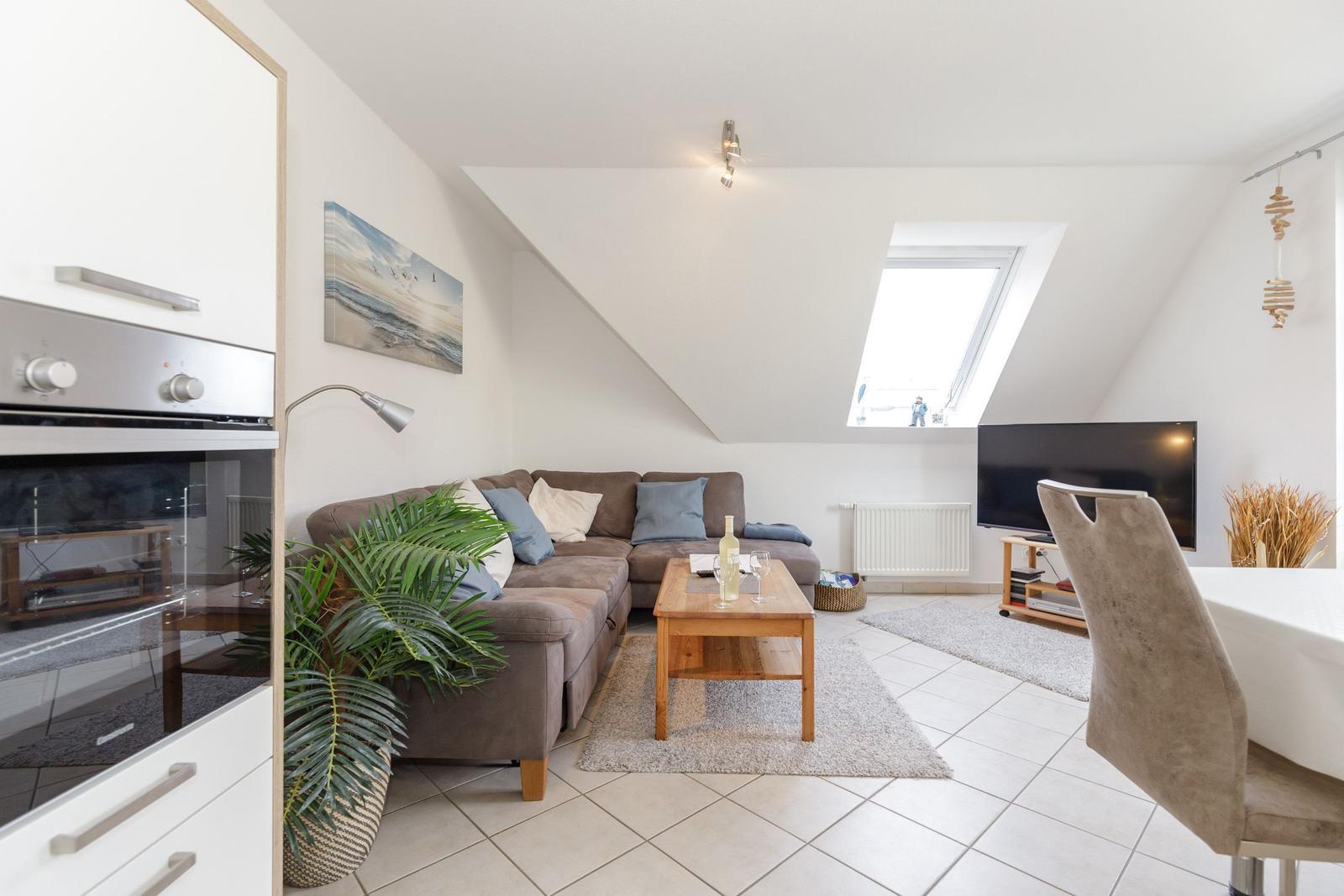 Wohn- und Essbereich mit Sofa, TV und Dachfenster.