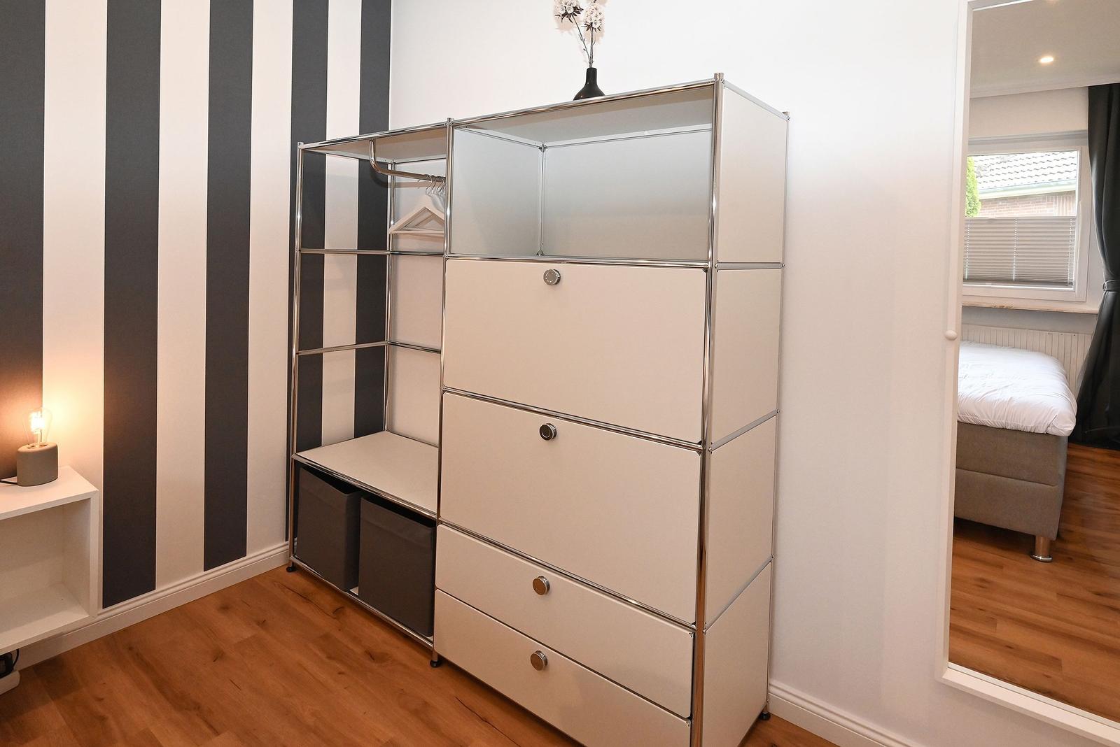 Schlafzimmer mit Kleiderschrank, Spiegel und gestreifter Wand