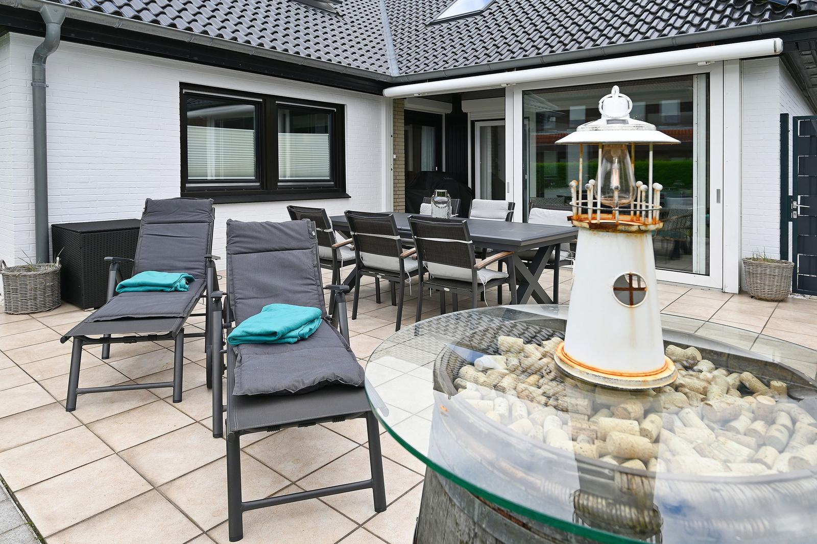Terrasse mit Liegestühlen, Esstisch und Laterne auf Korken