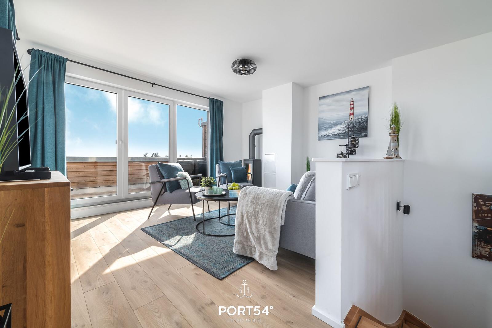 Wohnzimmer mit großem Fenster, Sofa und Couchtisch. Blick auf Balkon mit Holzgeländer.
