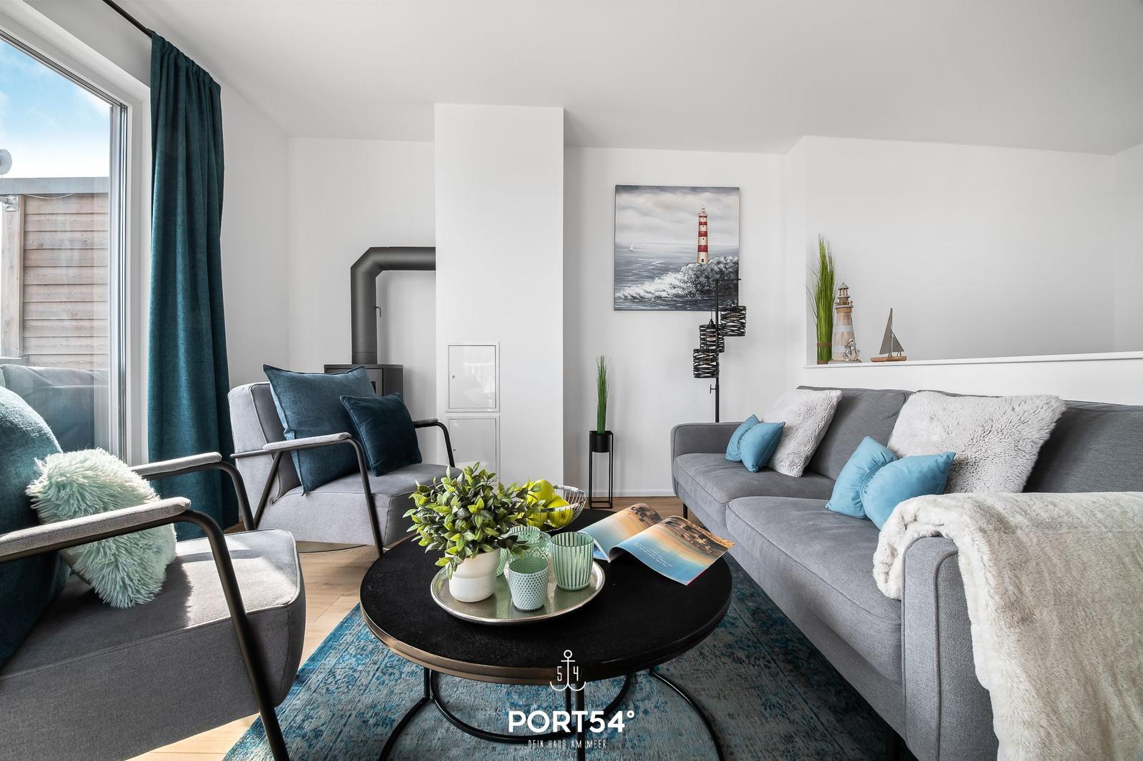 Wohnzimmer mit Sofa, Sesseln und Tisch. Wandbild und Dekoration mit Leuchtturmthema.