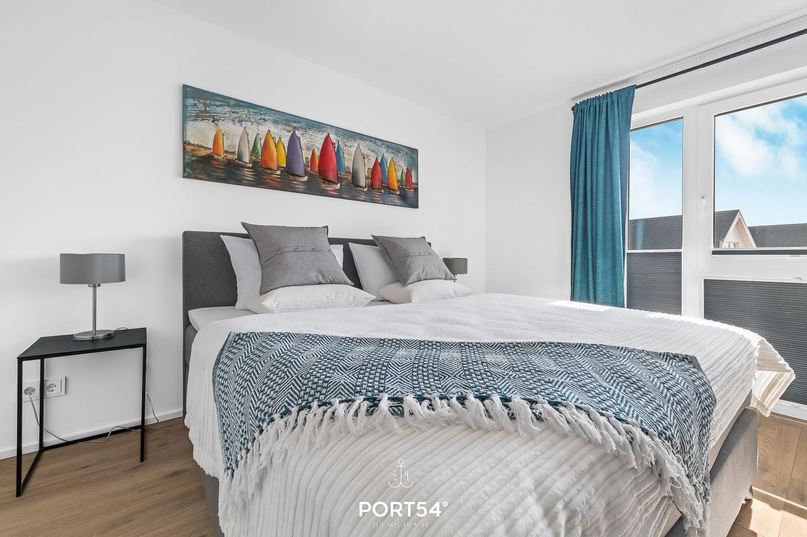 Schlafzimmer mit Bett, Wandbild und Fenster mit Blick.
