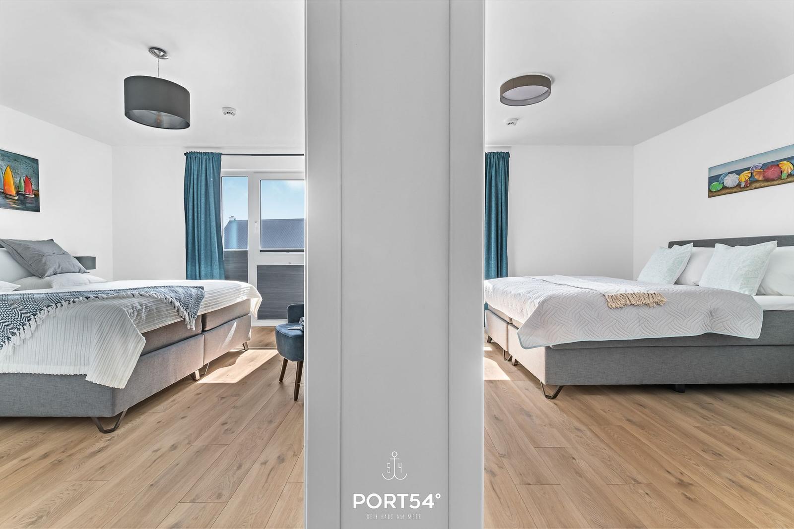 Schlafzimmer mit Bett, Fenster und Holzboden. Wandbild und Vorhänge.