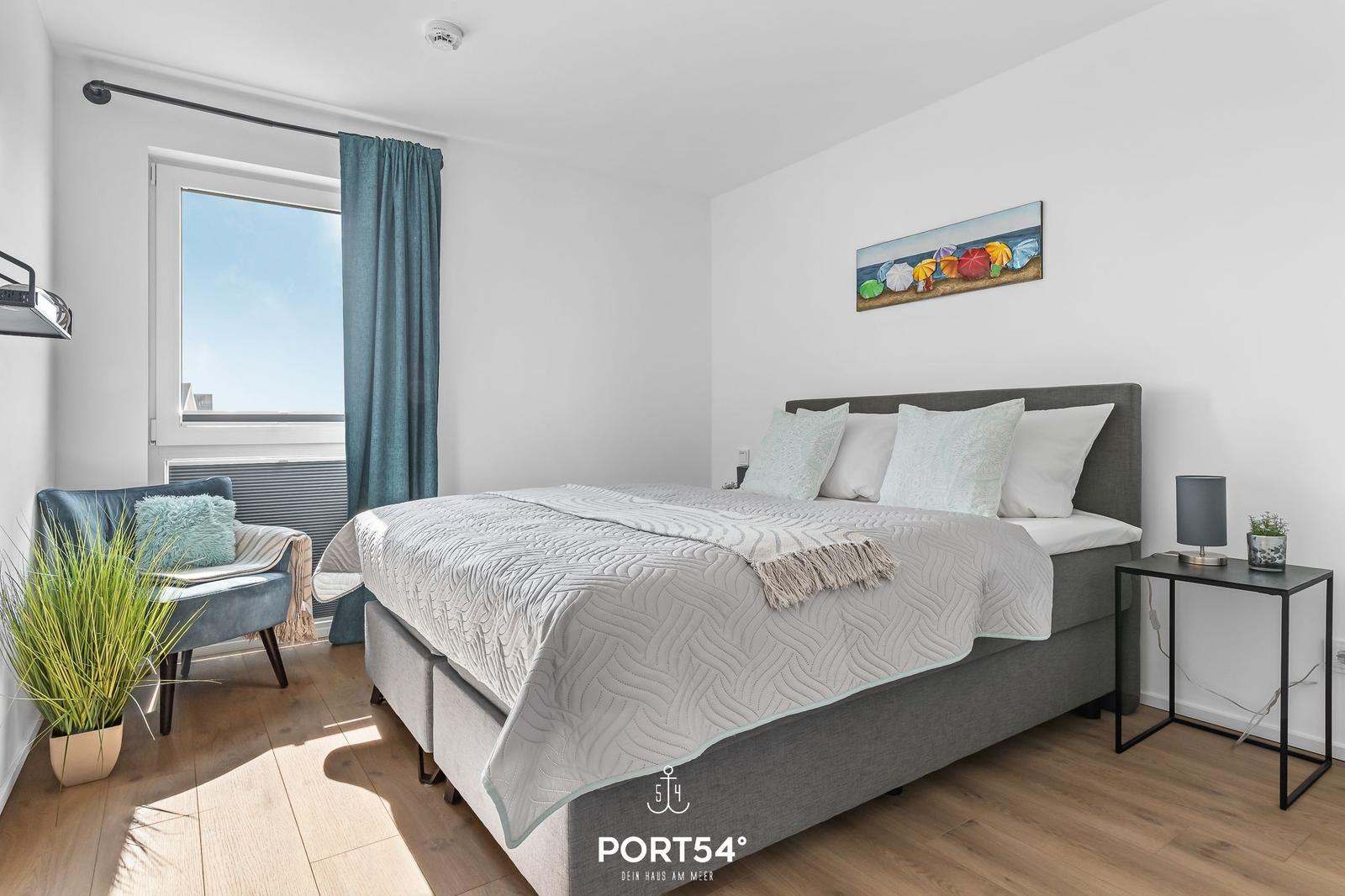 Schlafzimmer mit Bett, Fenster und Wandbild.