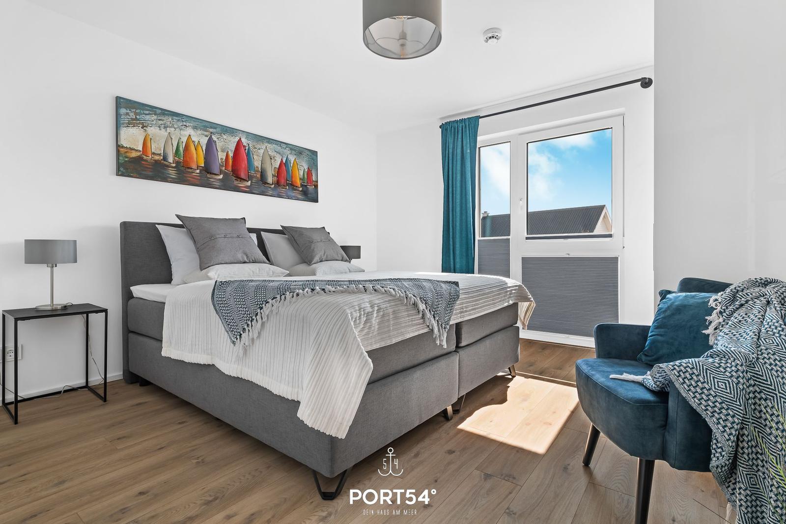 Schlafzimmer mit Bett, Sessel und Fenster zur Aussicht.