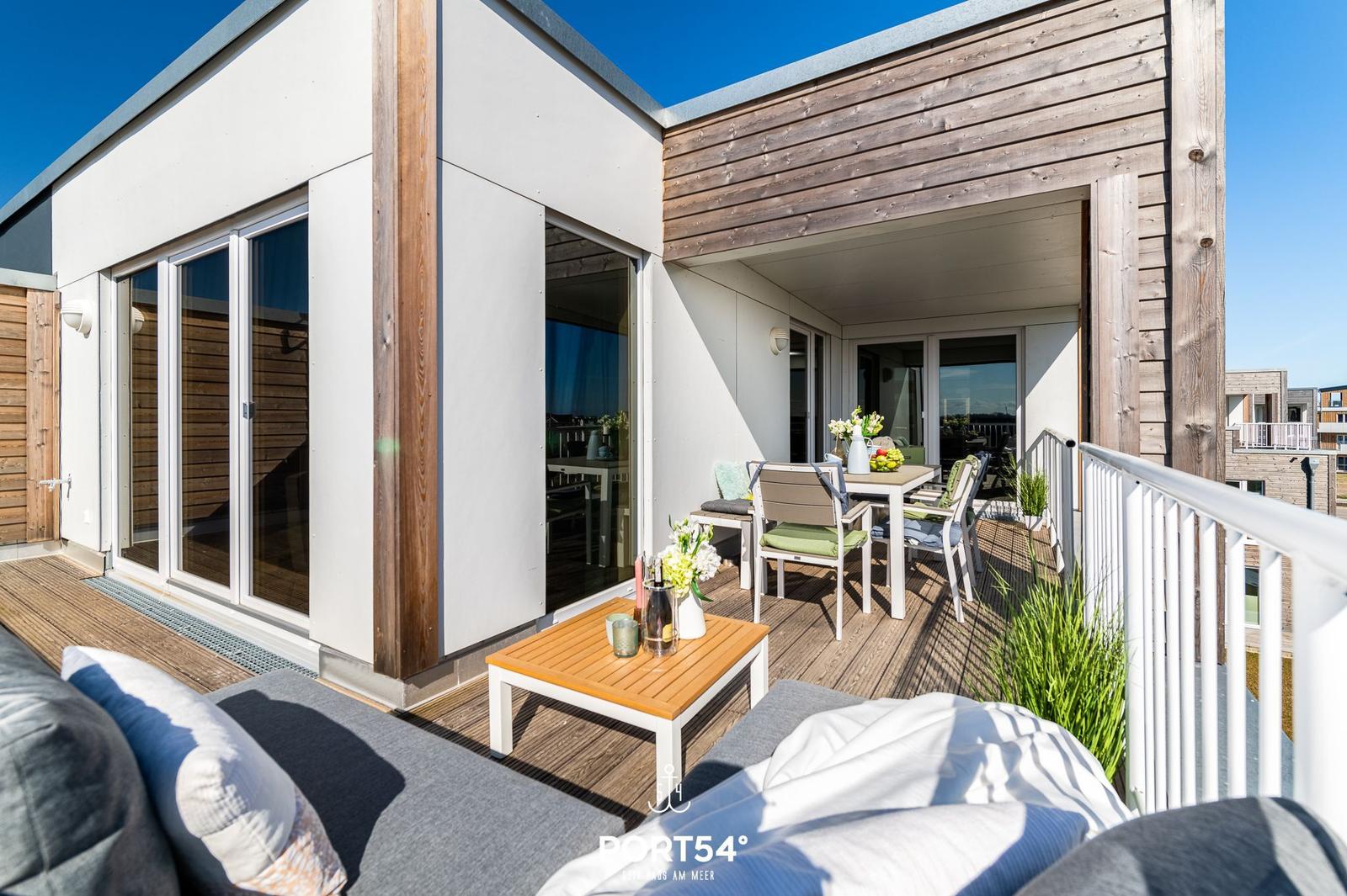 Terrasse mit Sitzgelegenheiten und Tisch. Moderne Architektur mit Holz und Glas.