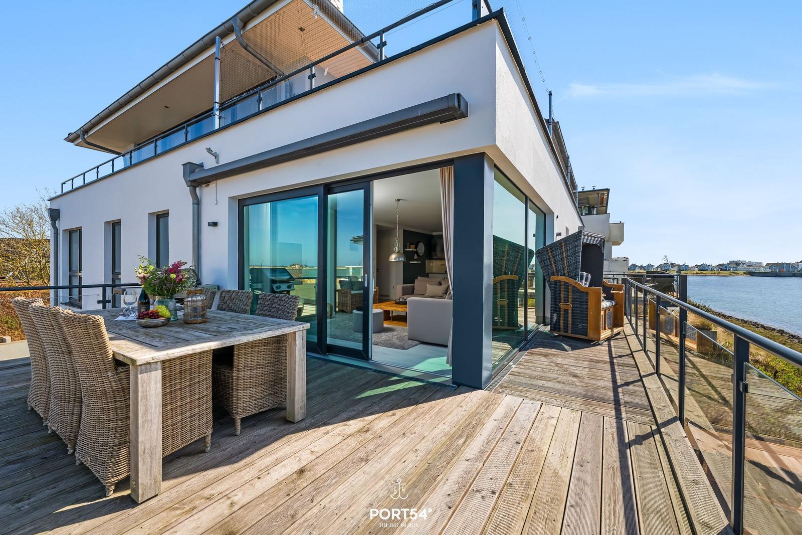 Terrasse mit Esstisch, Gartenmöbeln und Blick auf Wasser