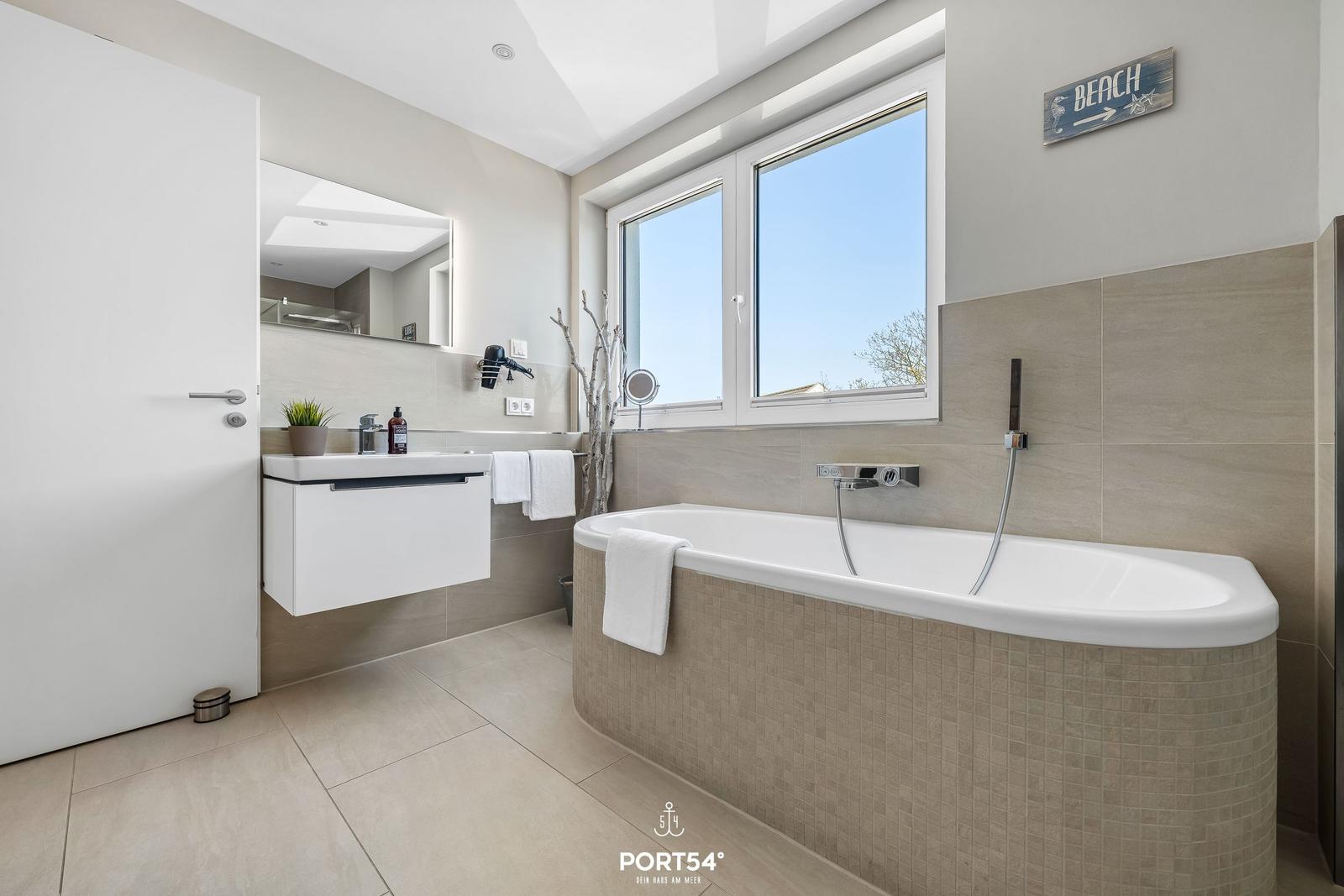 Badezimmer mit Badewanne, Fenster und Waschbecken