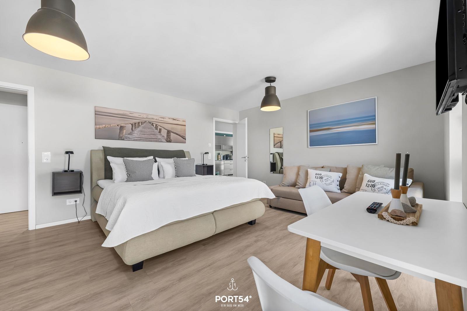 Schlafzimmer mit Bett, Sofa und Esstisch. Wandbilder und moderne Beleuchtung.