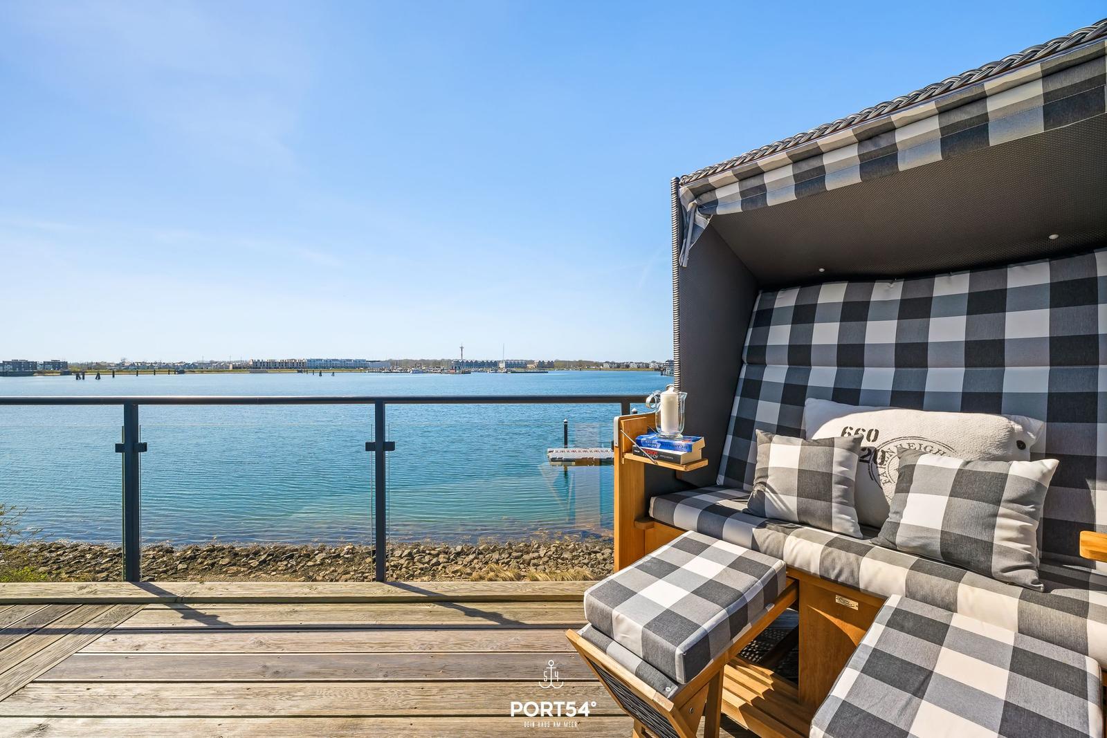 Terrasse mit Strandkorb und Blick auf das Wasser.
