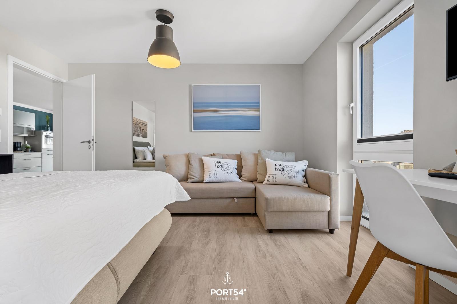 Schlafzimmer mit Sofa, Bett und Blick aufs Meer.
