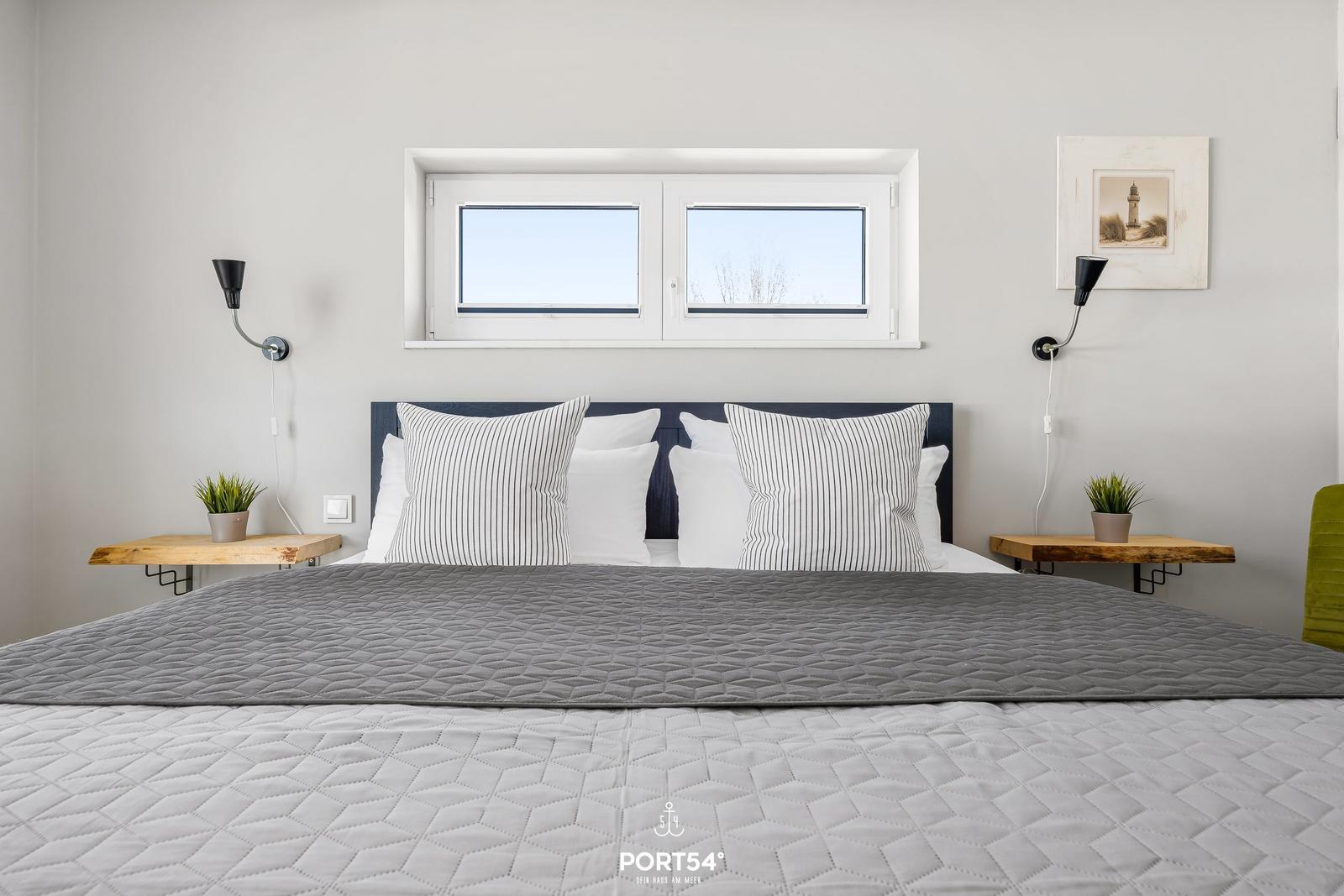 Schlafzimmer mit Bett, Fenster und Nachttischen.