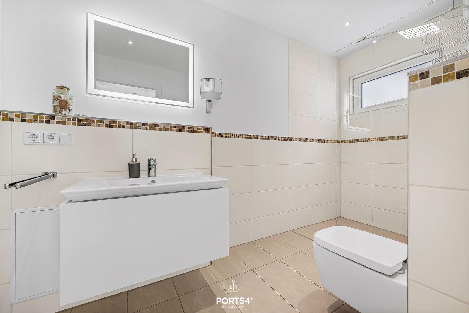Bad mit Waschtisch, Spiegel, Toilette und Dusche.