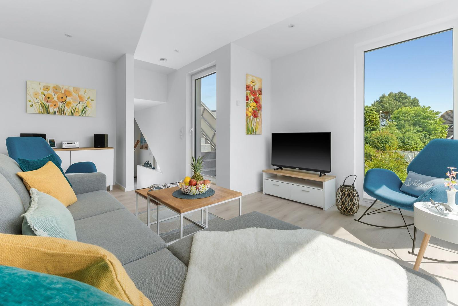 Living room with sofa, TV, and view of green trees.