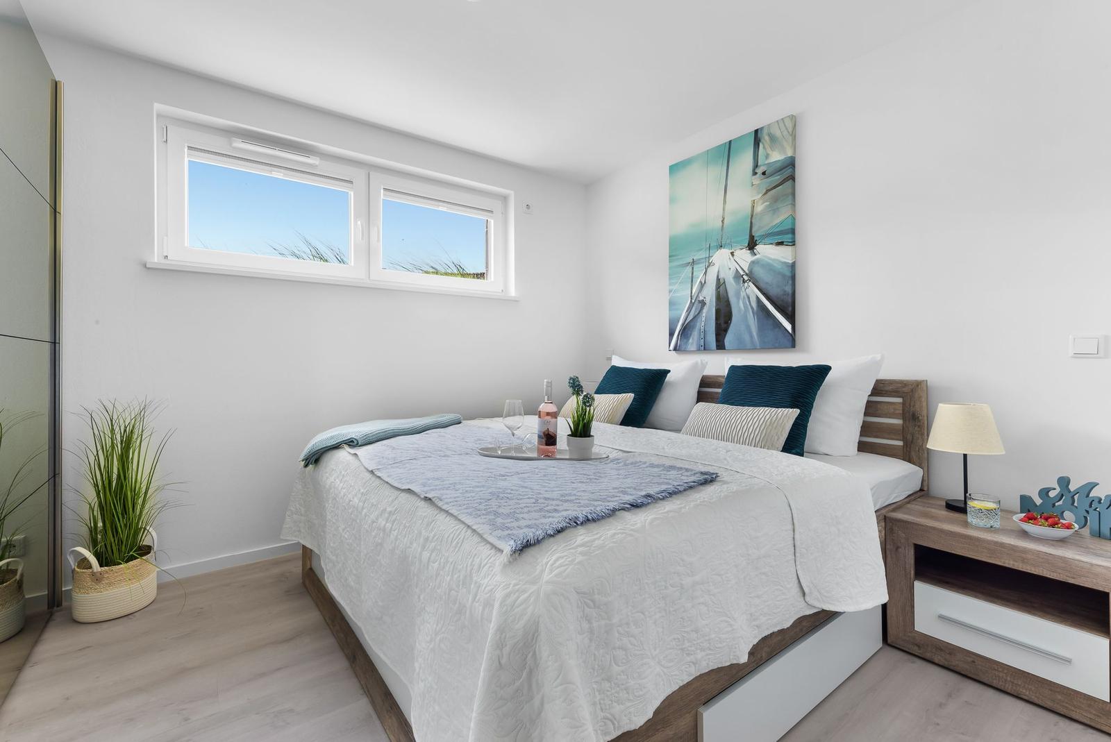 Bedroom with bed, nightstand, and wall art. Window shows grass and sky.