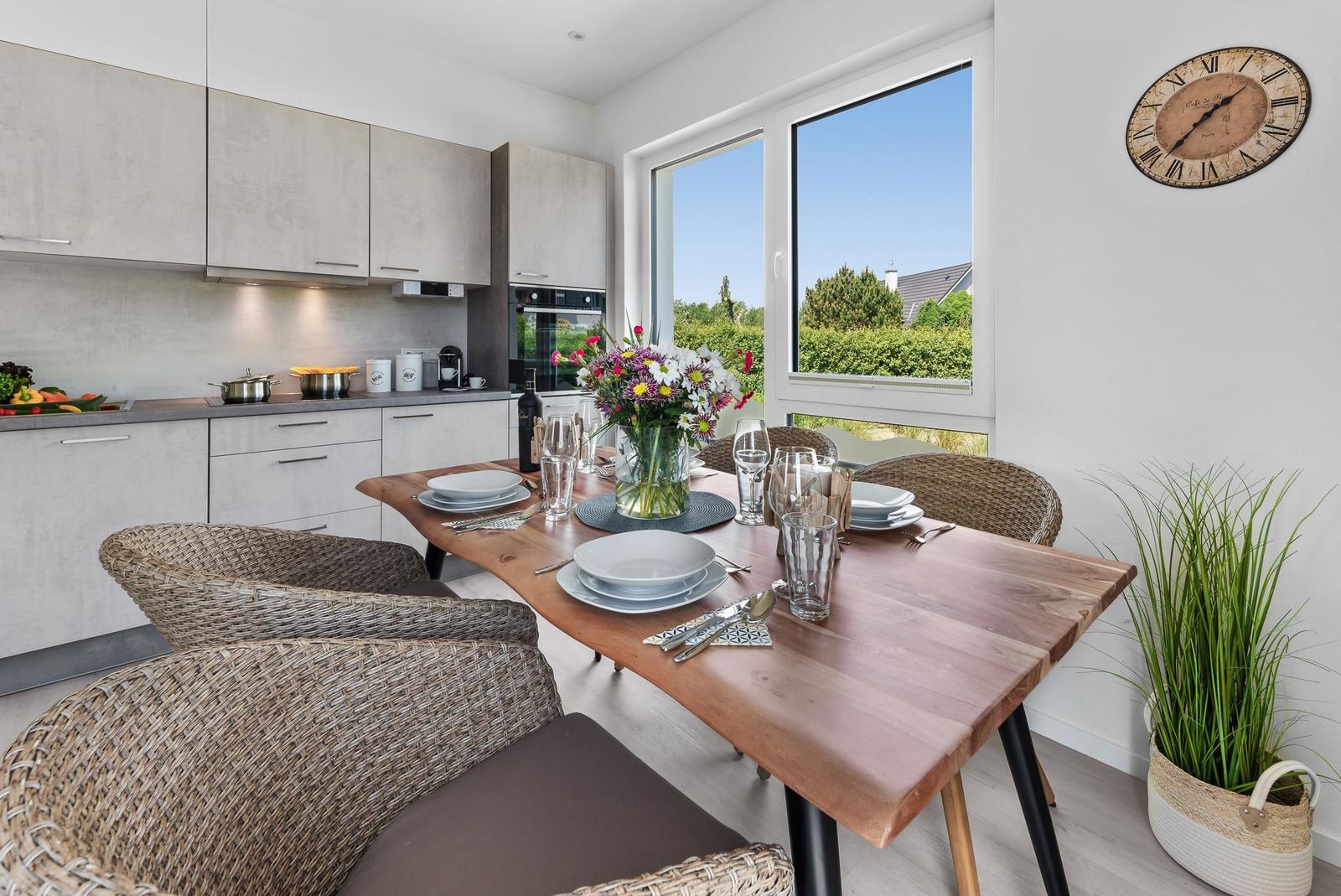 Dining area with wooden table, chairs, and view of greenery.