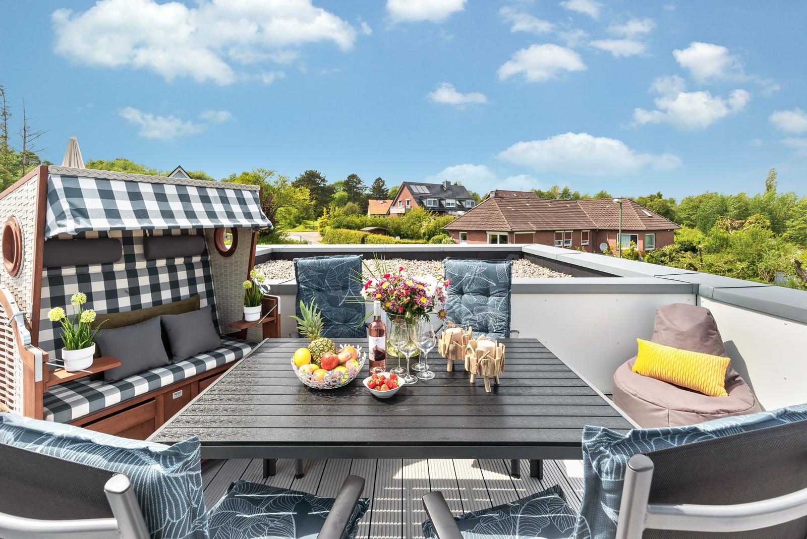 Terrace with table, chairs, and beach cabana. View of houses and trees.