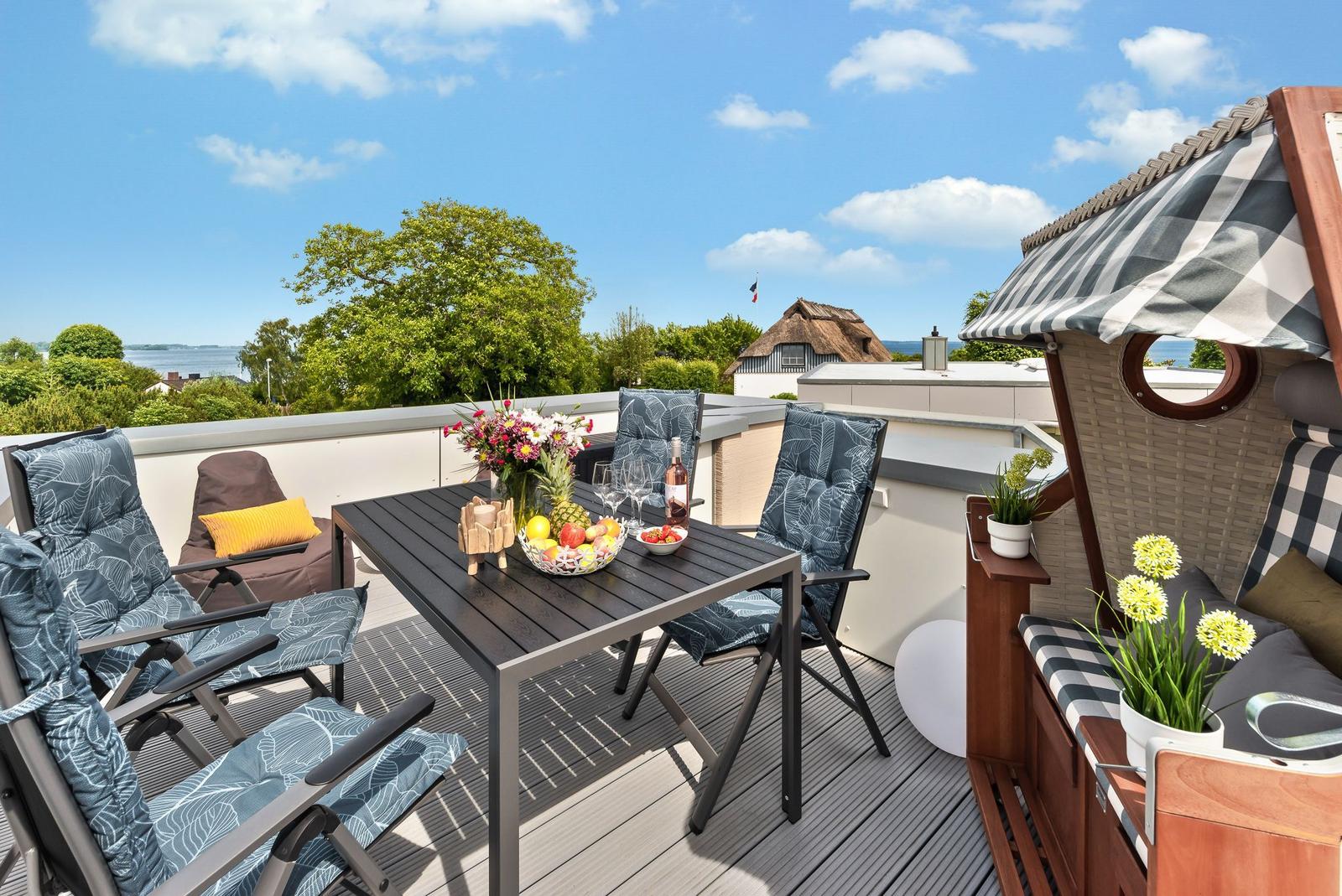 Terrace with table, chairs, and view of water and greenery.