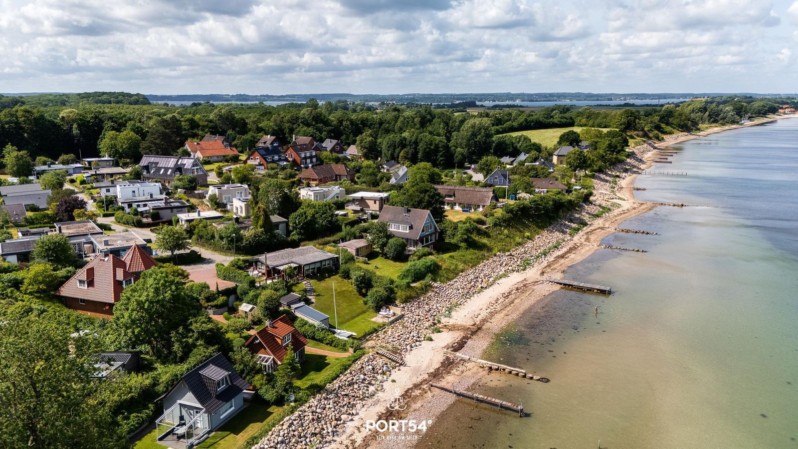 Houses by the shore with view of water and forest