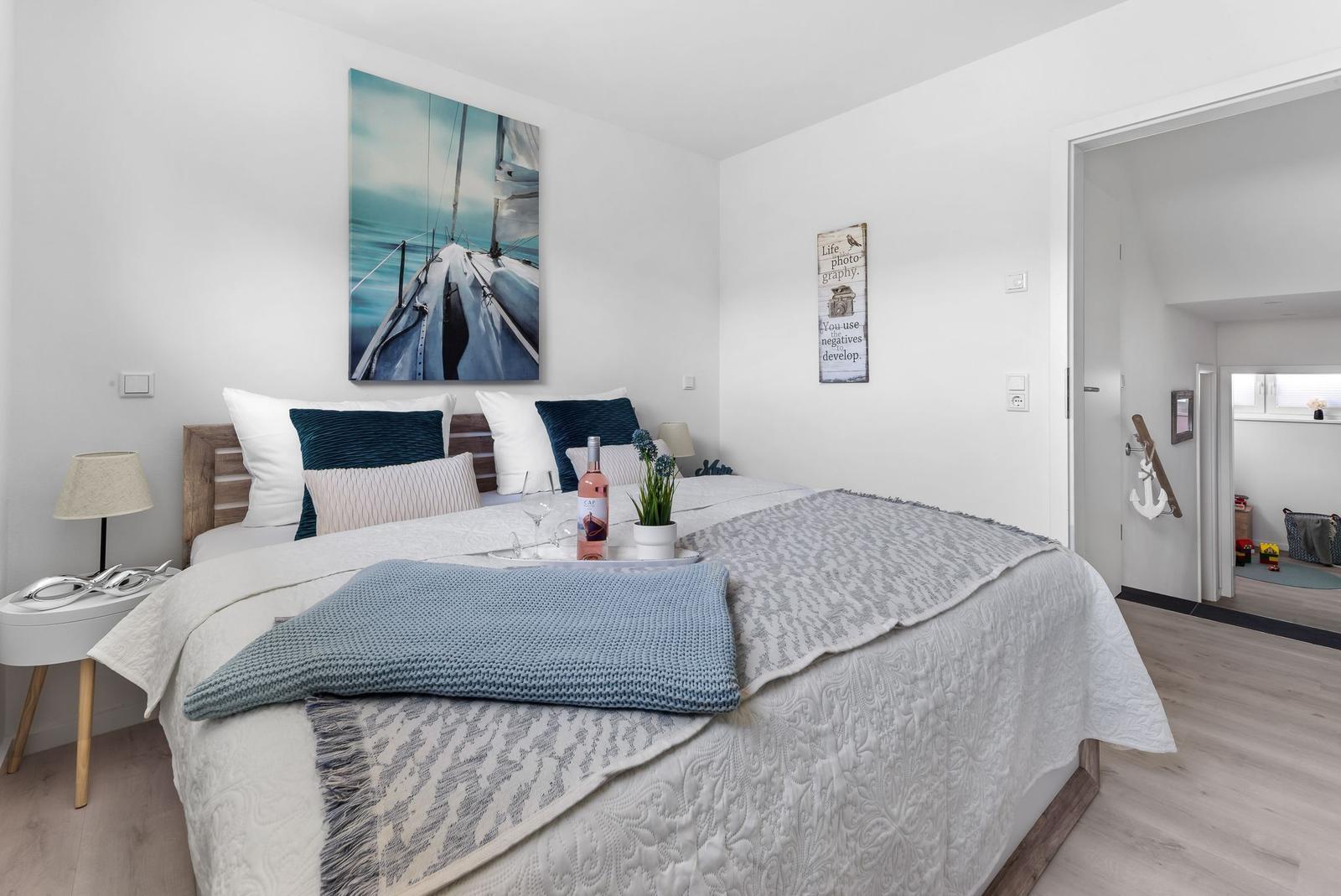Bedroom with bed, wall art, and view into hallway.