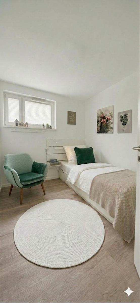 A bedroom with a bed, a chair, and a round rug.
