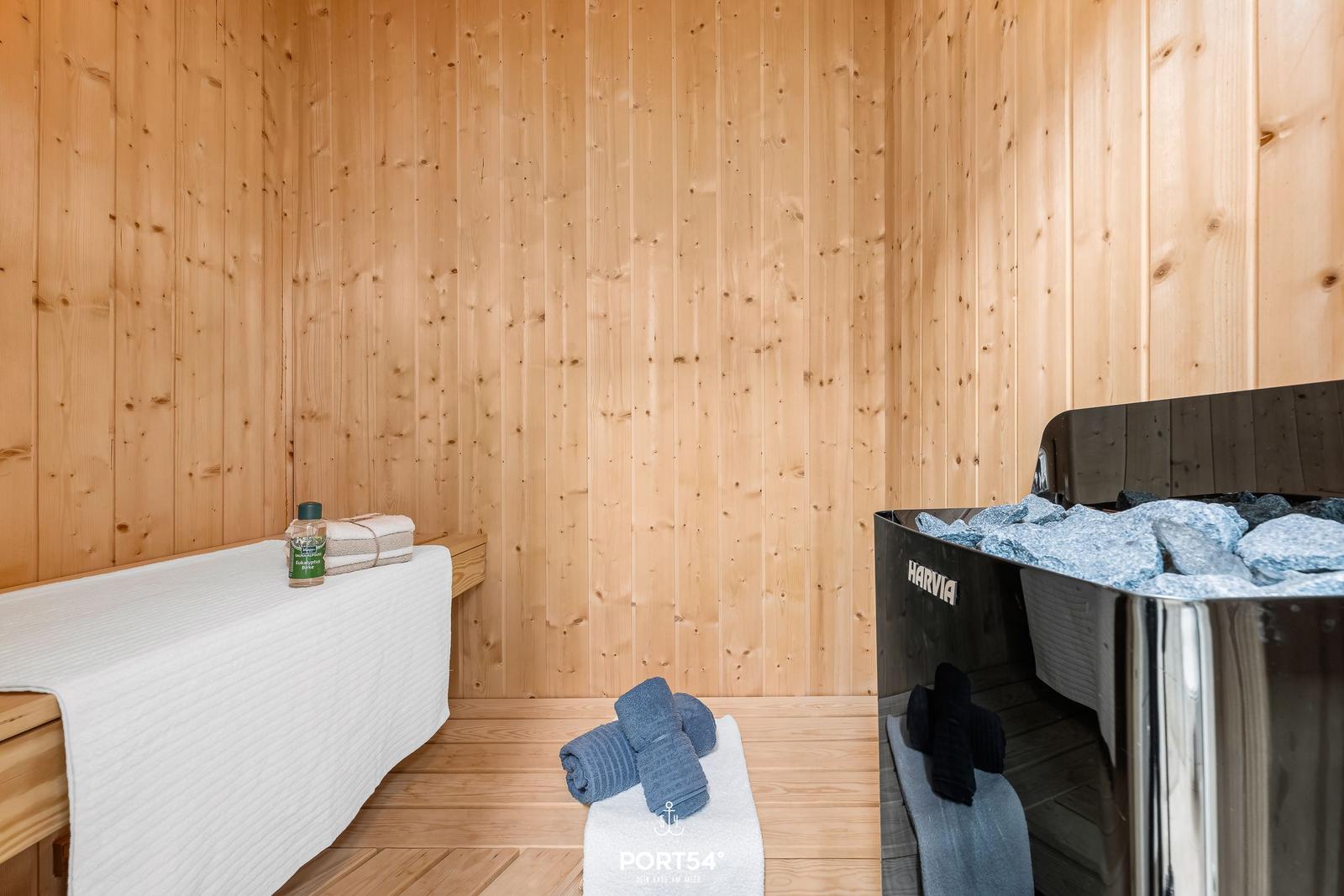 Sauna mit Holzwand, Bank, Steine und Handtüchern.