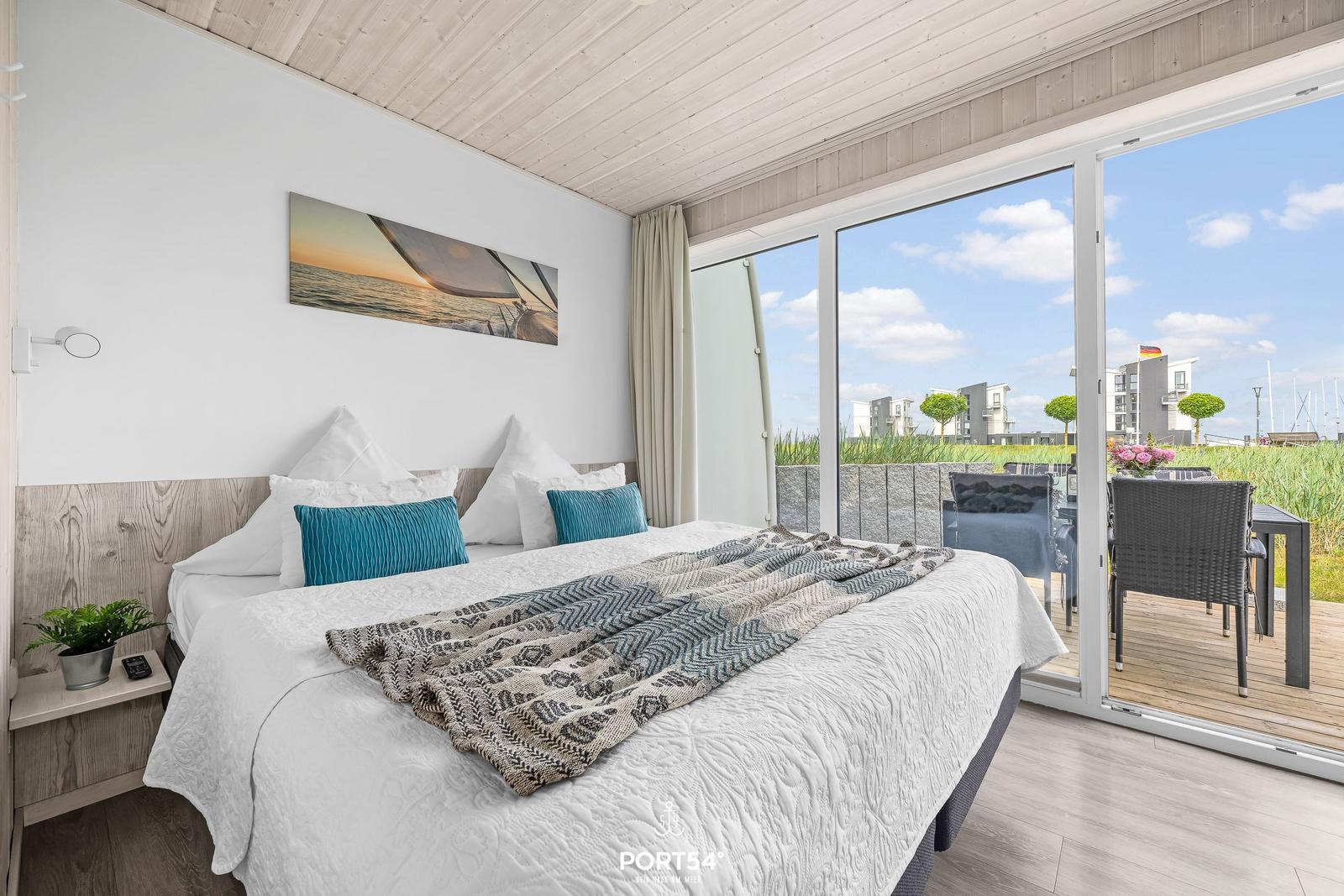 Schlafzimmer mit Balkon und Meerblick. Bett, Wandbild und Terrasse sichtbar.