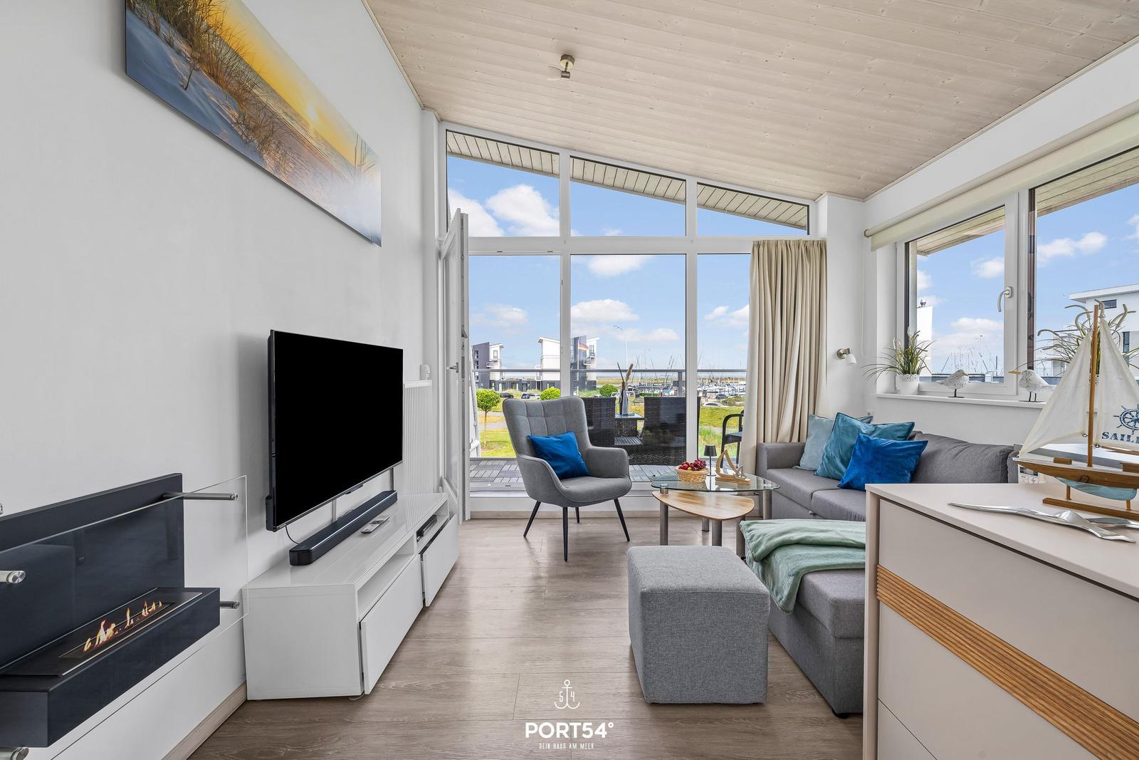 Wohnzimmer mit Fernseher, Kamin und Blick auf den Hafen.