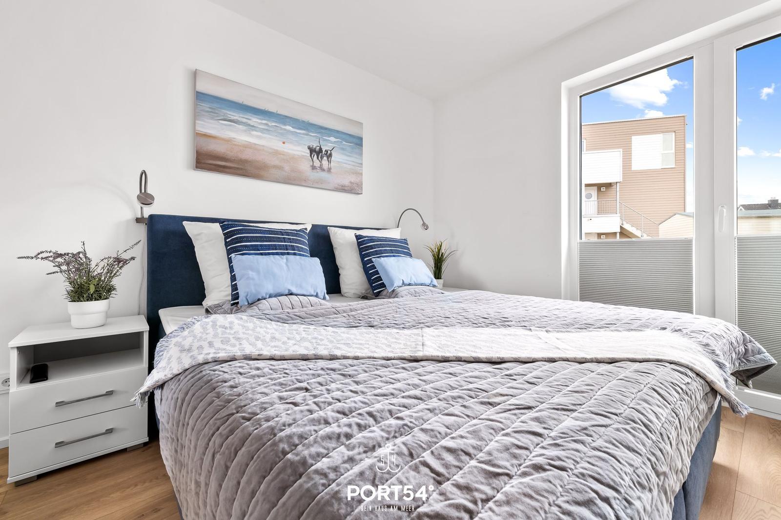Schlafzimmer mit Bett, Nachttisch und Fenster zur Aussicht.