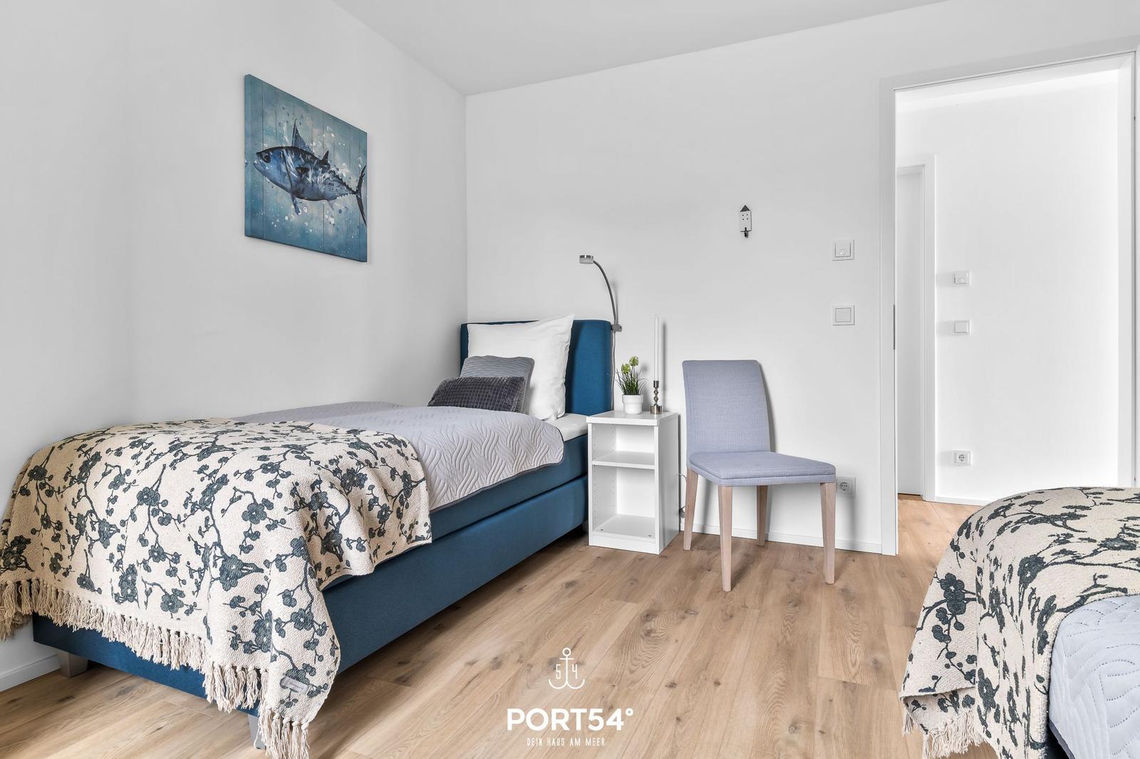 Schlafzimmer mit blauer Matratze, Holzboden und Wandbild eines Fisches.