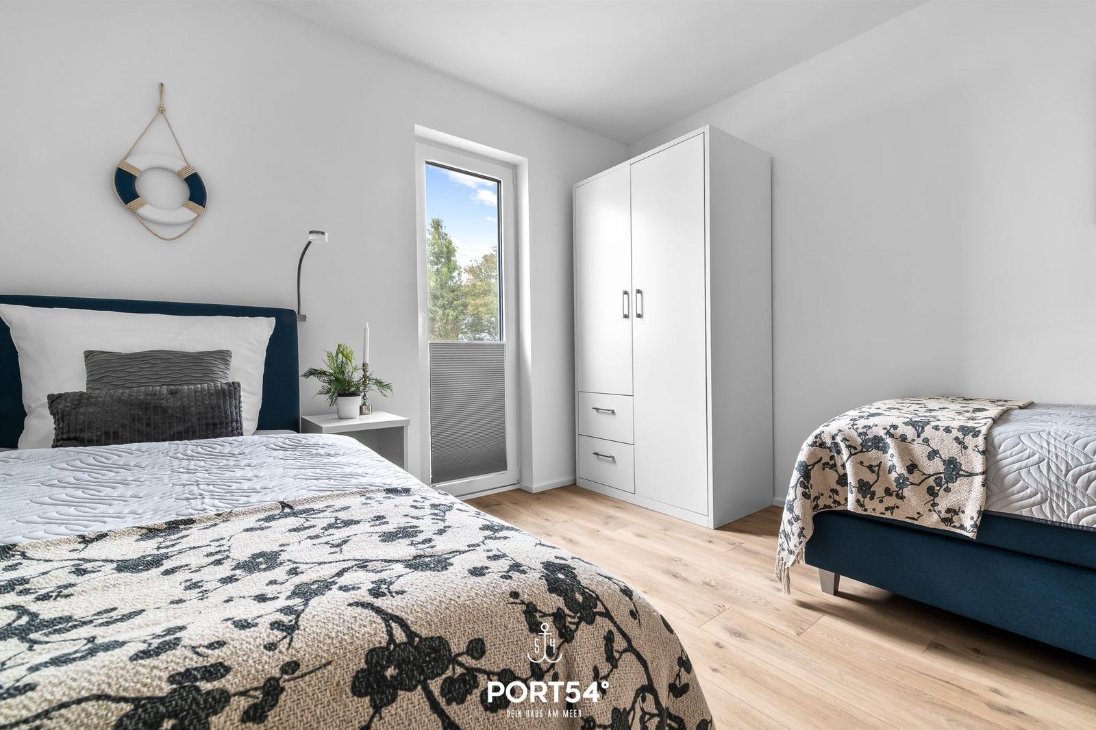 Schlafzimmer mit zwei Betten, Kleiderschrank und Fenster zur Aussicht.