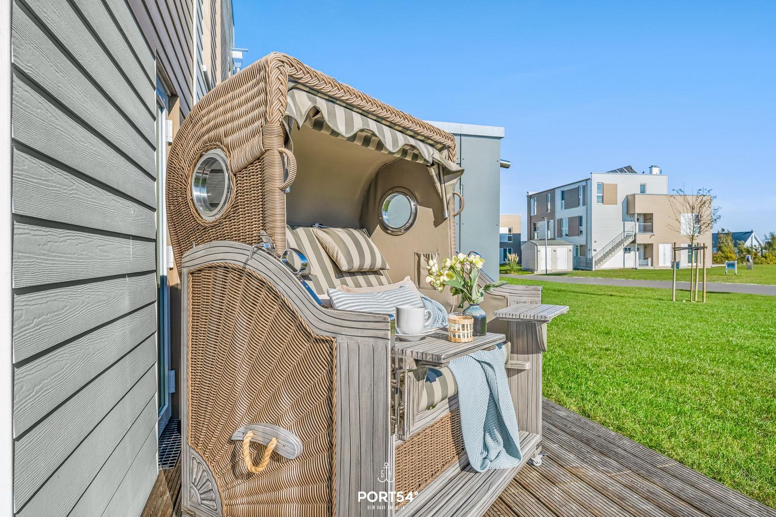 Wicker Strandkorb mit Sitz und Tisch auf Terrasse neben Haus.