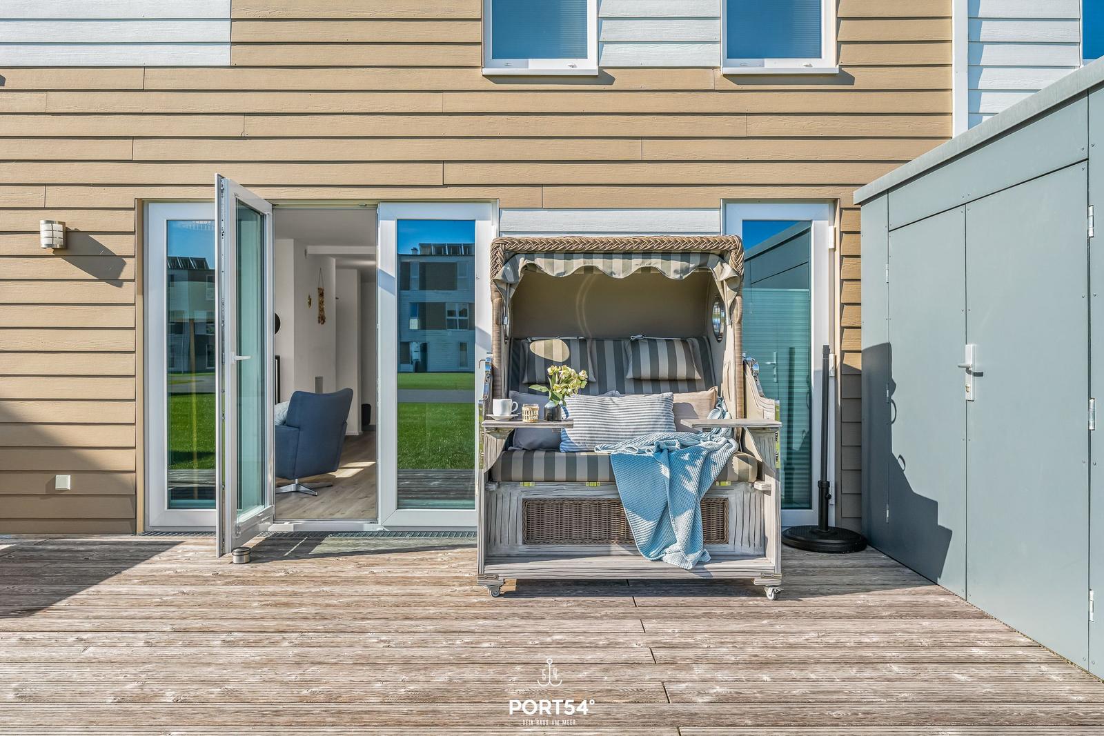 Terrasse mit Strandkörbe und Blick ins Haus. Holzdeck und Glastüren.