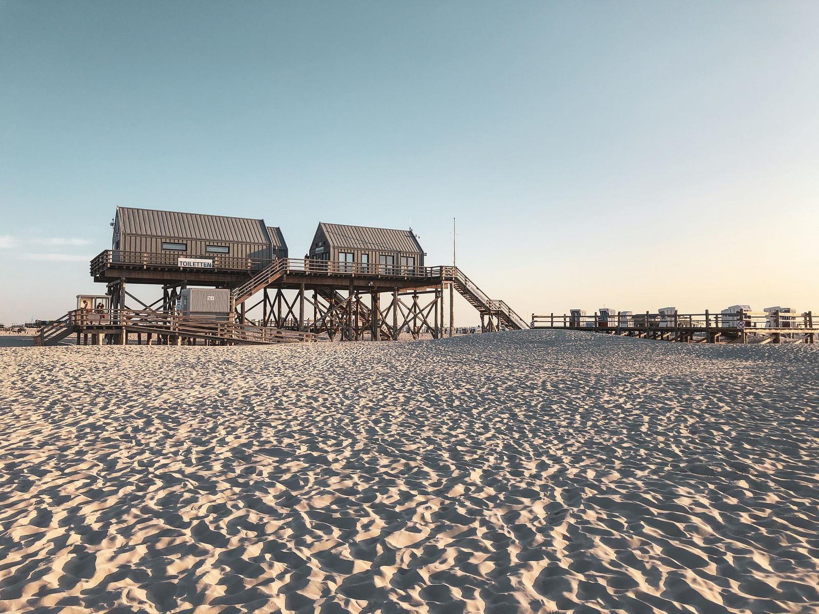 Zwei hölzerne Strandtoilettenhäuser auf Pfählen über Sand