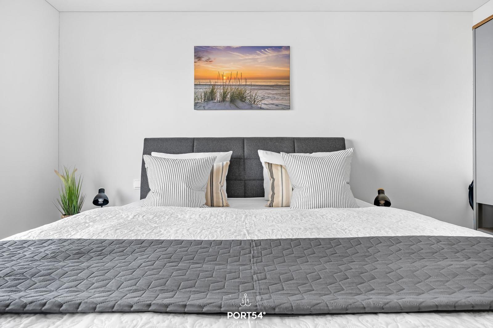 Schlafzimmer mit Bett, Kissen und Wandbild an der Wand.