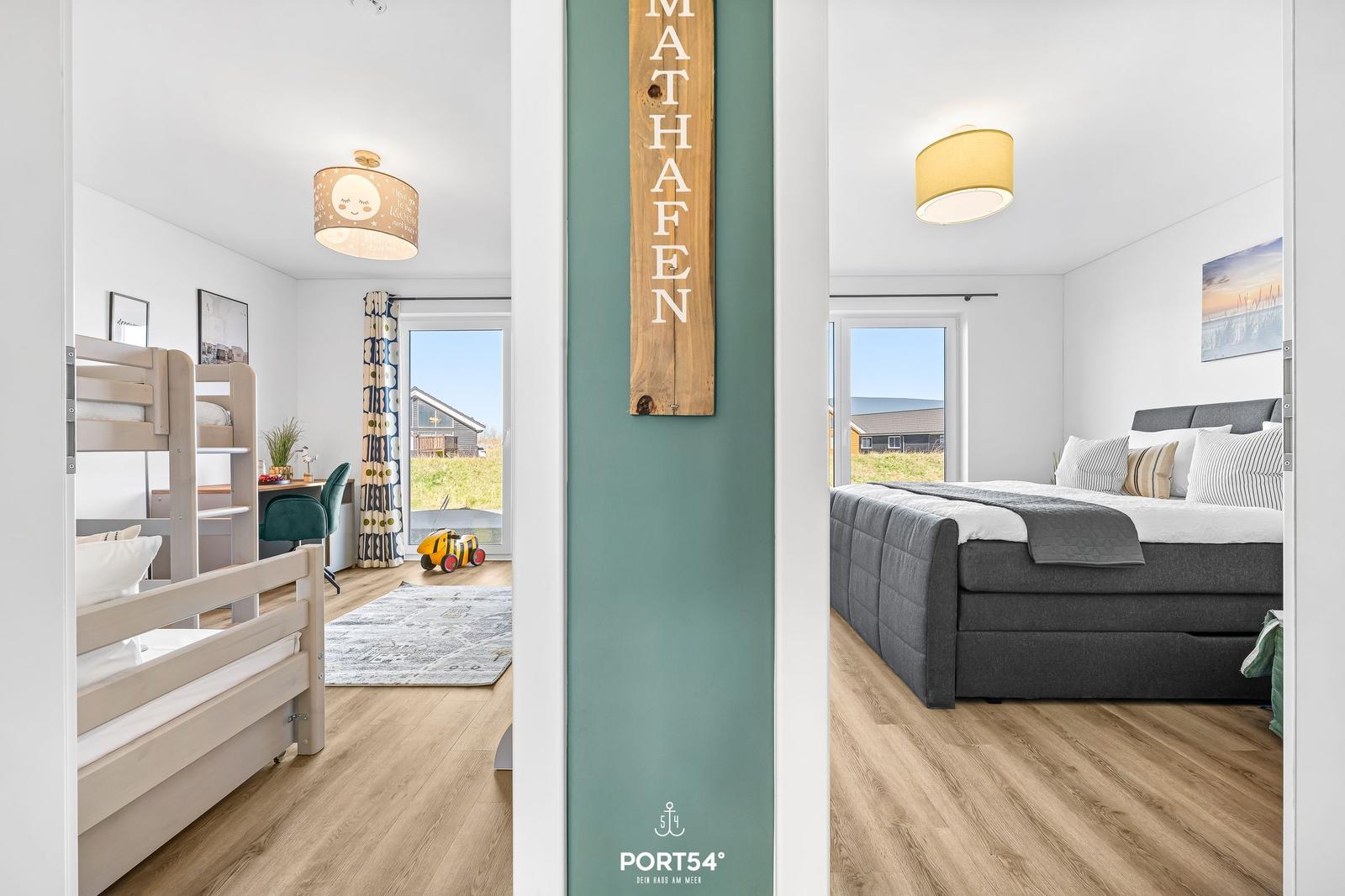 Zimmer mit Doppelbett und Kinderbereich mit Hochbett. Wand mit Holzschild MATHAFEN.