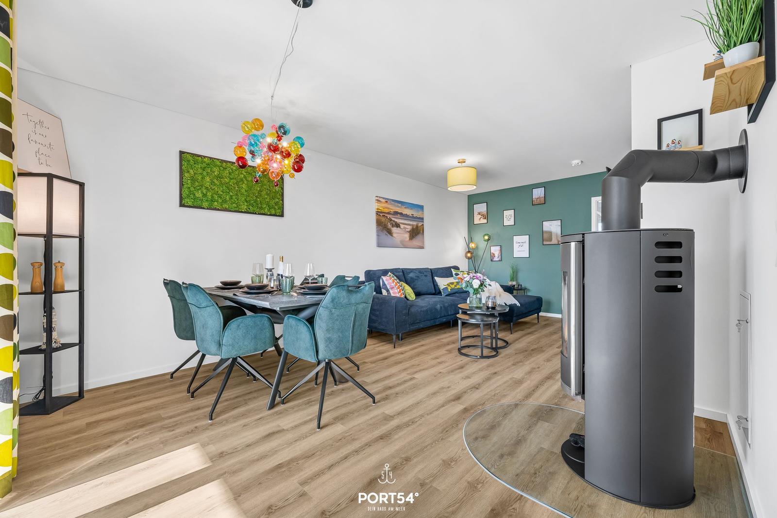 Wohn- und Essbereich mit Holzboden, Sofa, Esstisch und Kaminofen.
