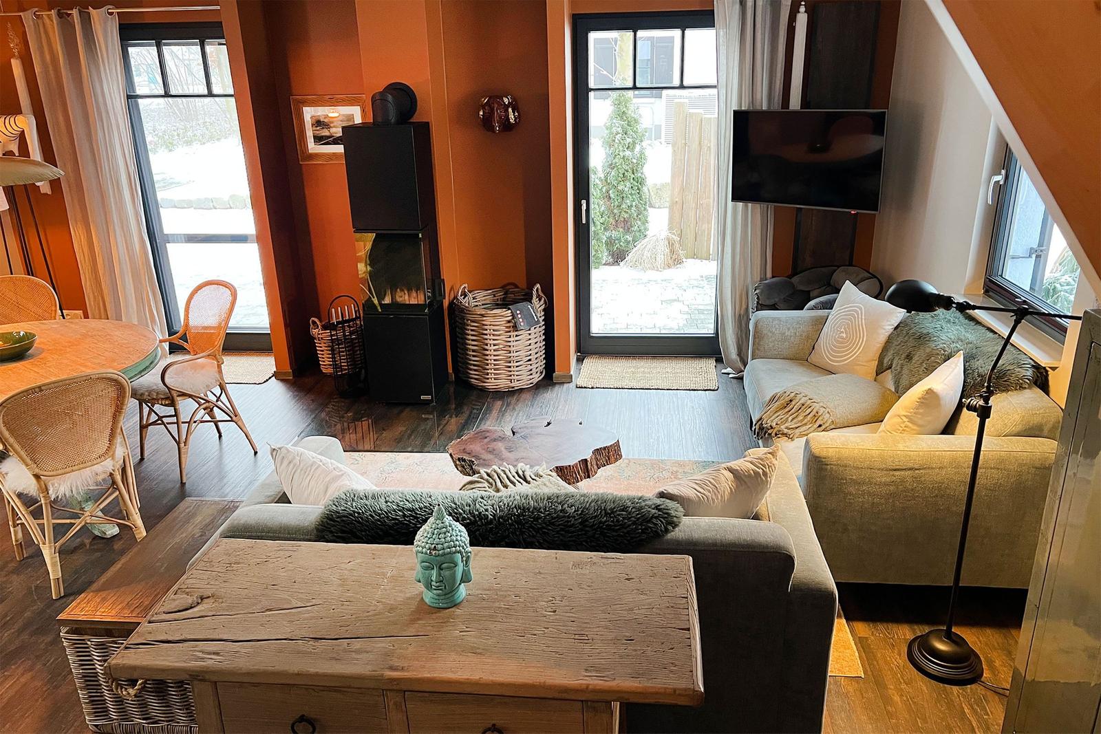 Wohnzimmer mit Sofa, Couchtisch und Fernseher. Durchgang zu Terrasse und Essbereich.