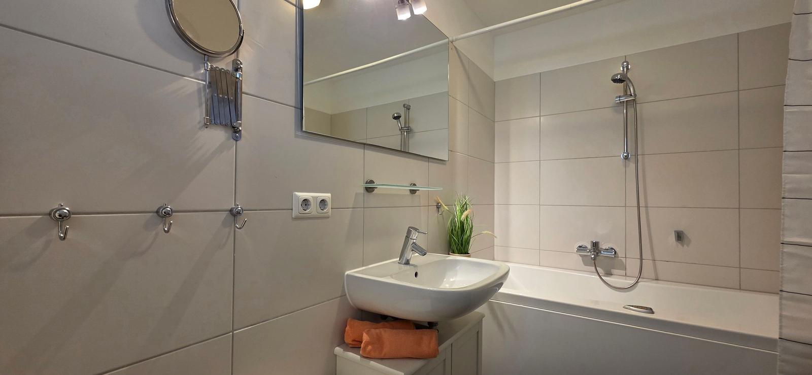 Badezimmer mit Badewanne, Dusche, Waschbecken und Spiegel.