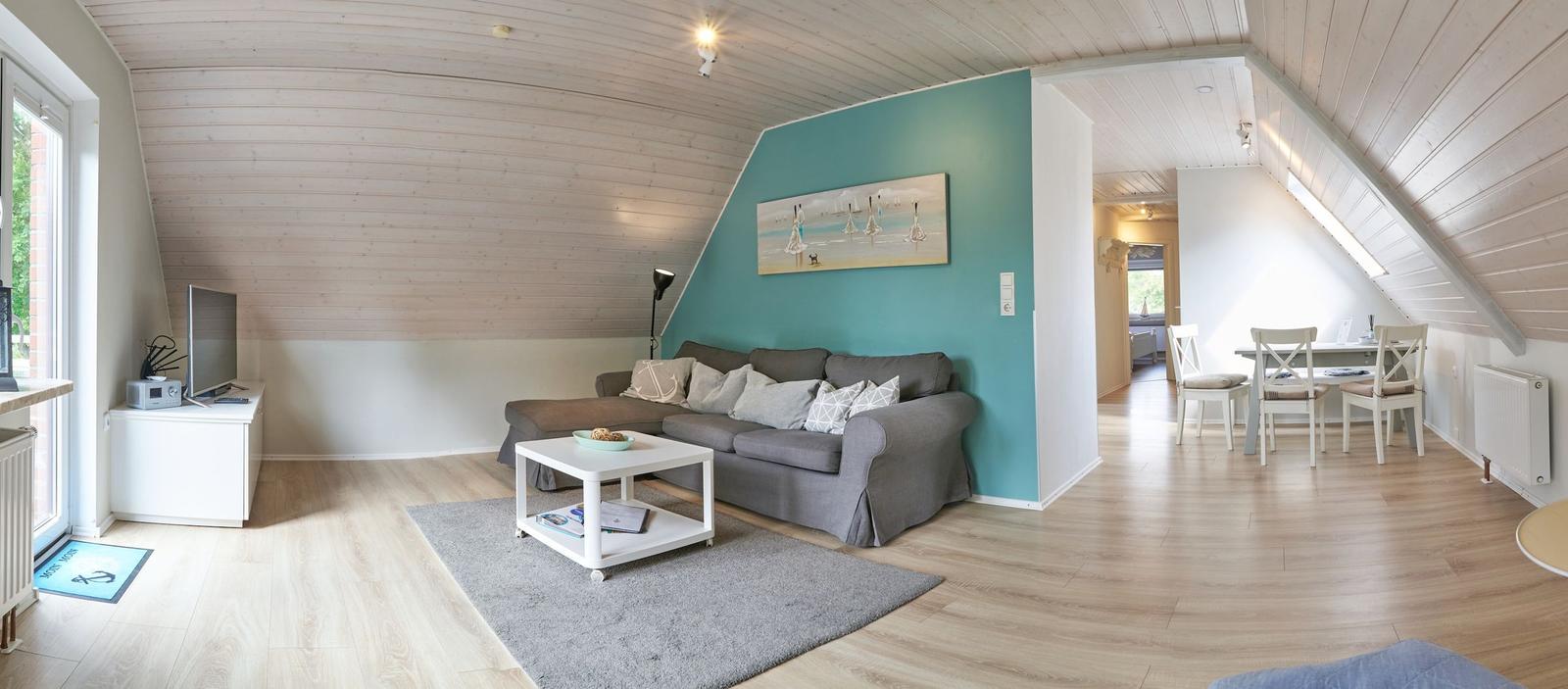 Wohn- und Essbereich mit Sofa, Tisch und Stühlen unter Holzdecke.