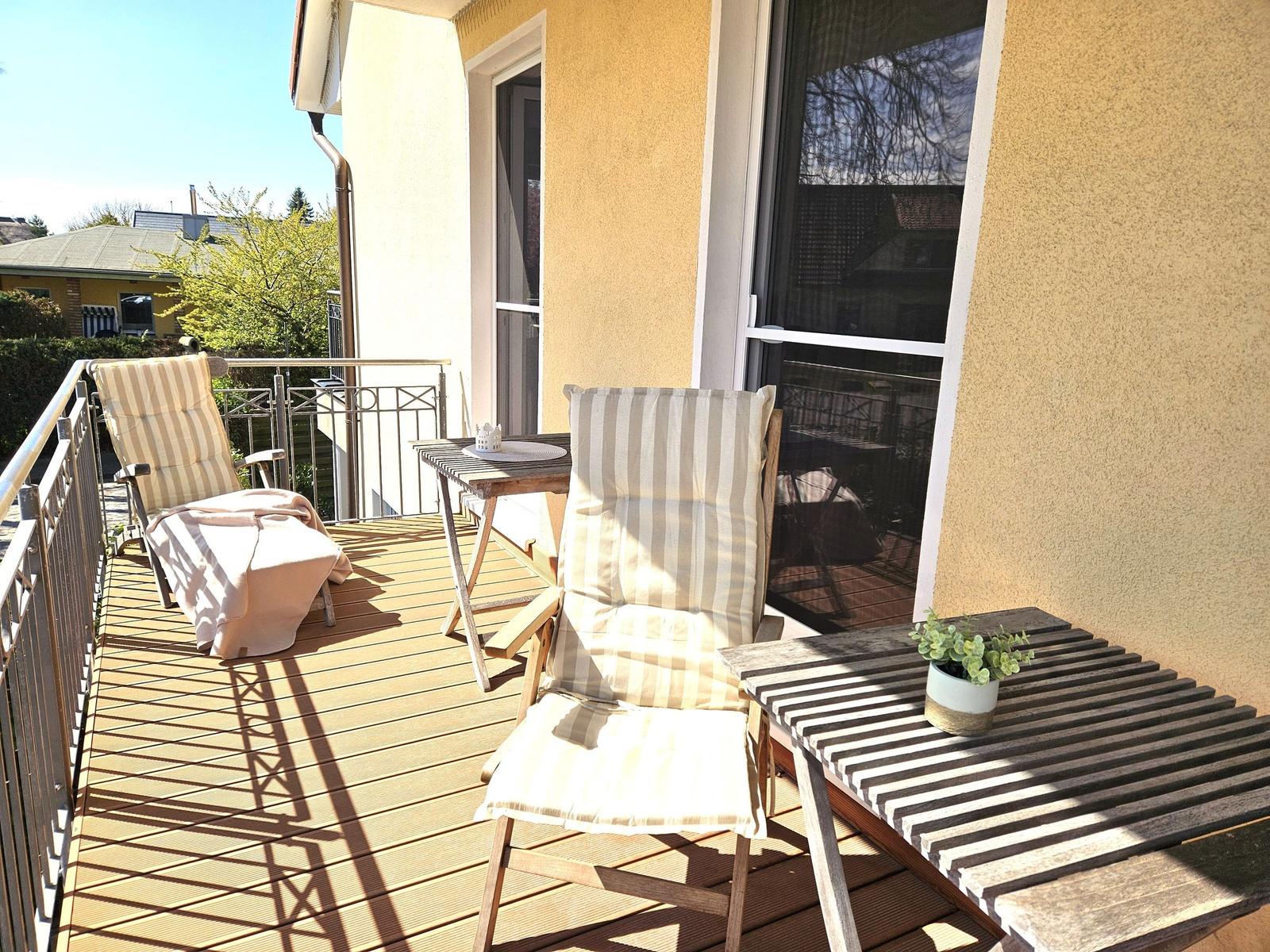 Terrasse mit zwei Liegestühlen, Tisch und Pflanze. Holzdecke und Geländer.