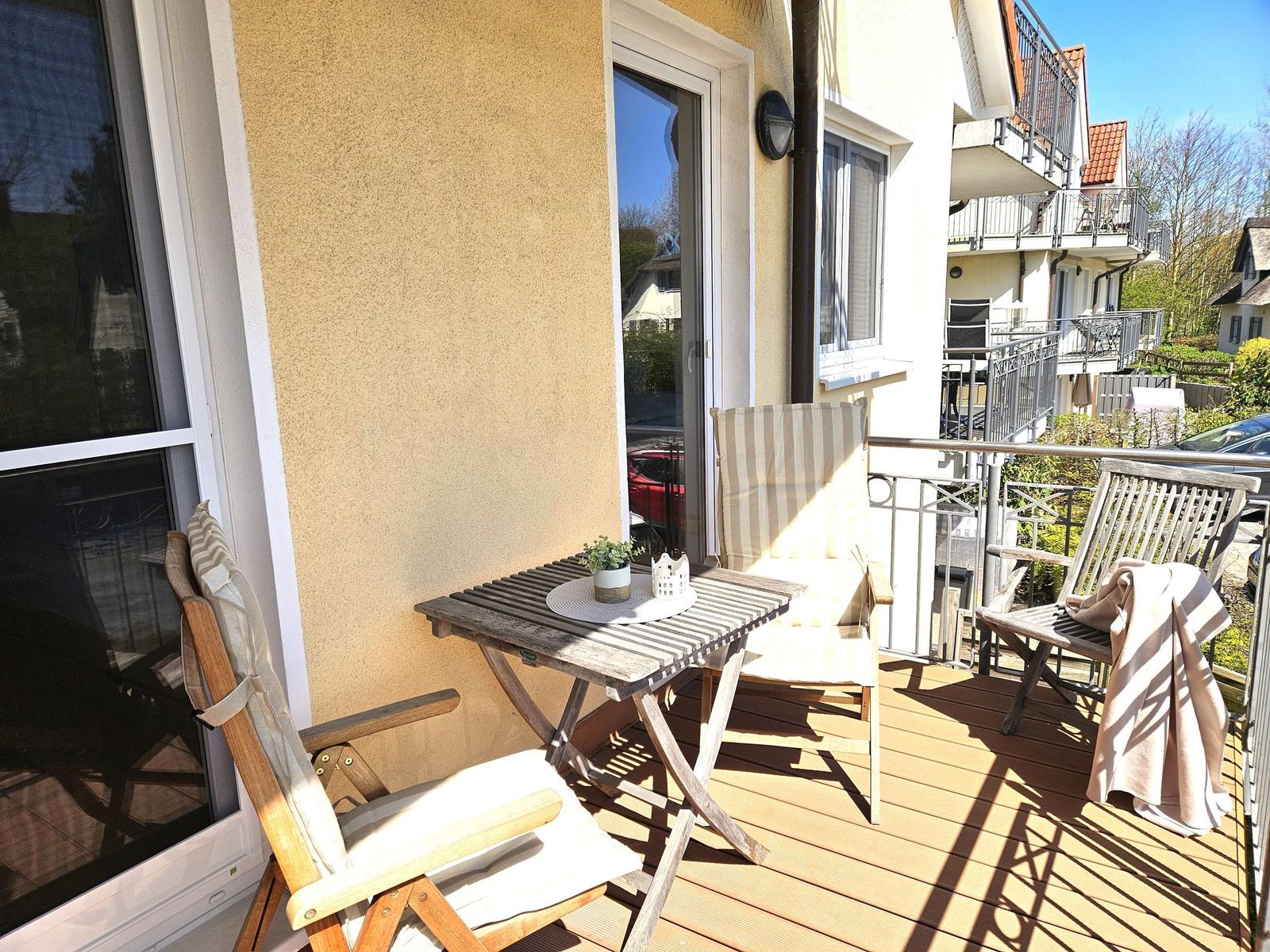 Terrasse mit Holztisch und drei Stühlen, Sonne, Blick auf Wohngebiet