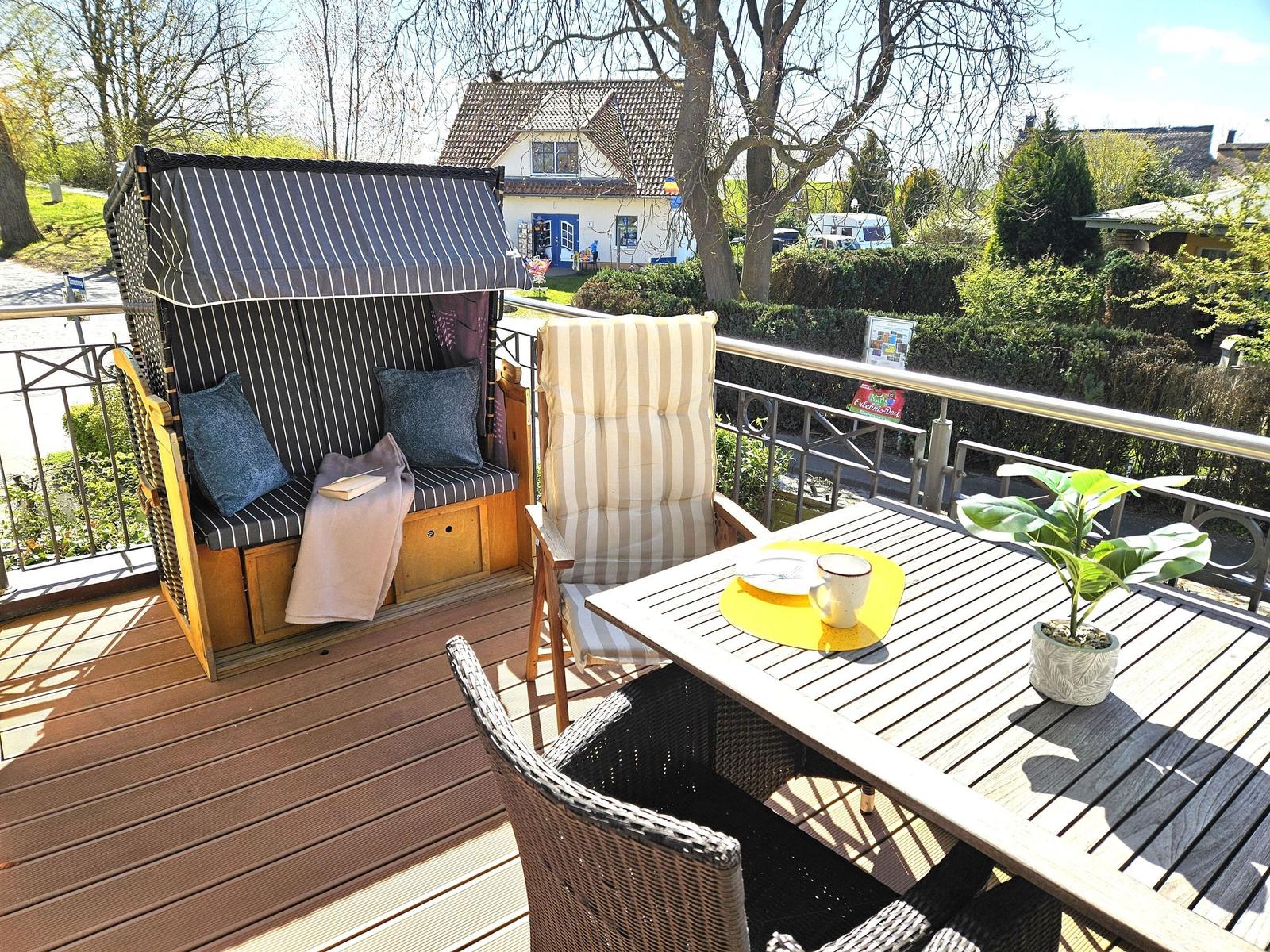 Terrasse mit Strandkorb, Sitzgruppe und Tisch mit Pflanze.