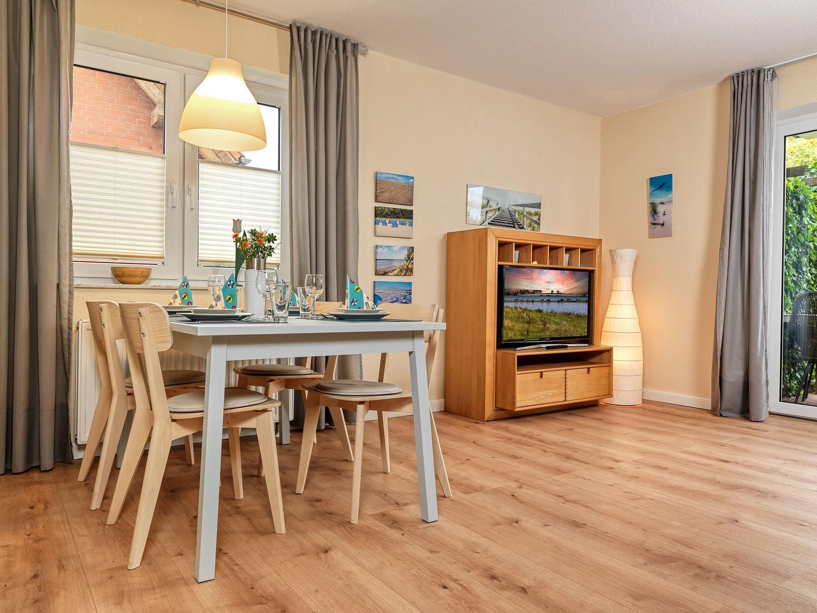 Essbereich mit Tisch und Stühlen, Fernseher und Fenster mit Blick auf Garten.