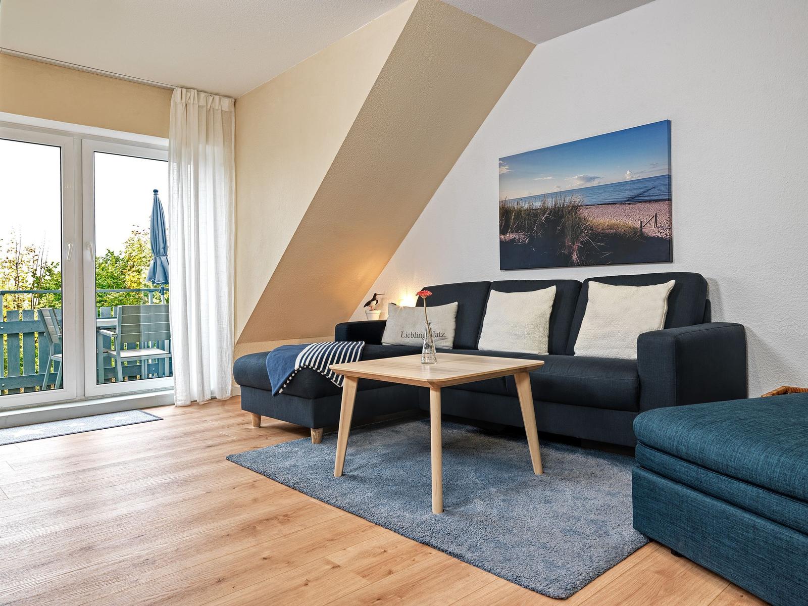 Wohnzimmer mit Sofa, Tisch und Balkonansicht.