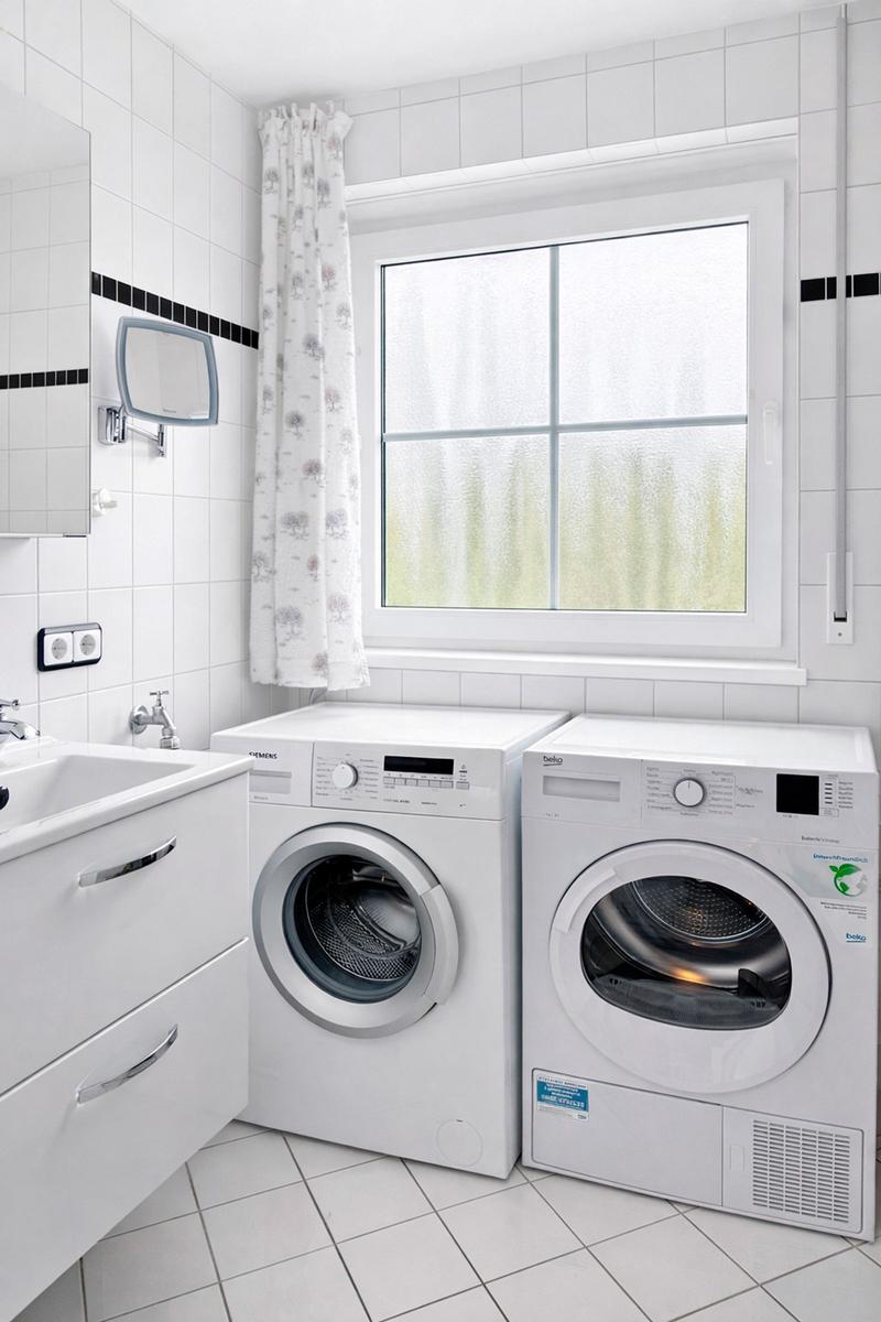 Wohnung mit Waschmaschine und Trockner, Fenster mit Vorhang und Waschbecken.