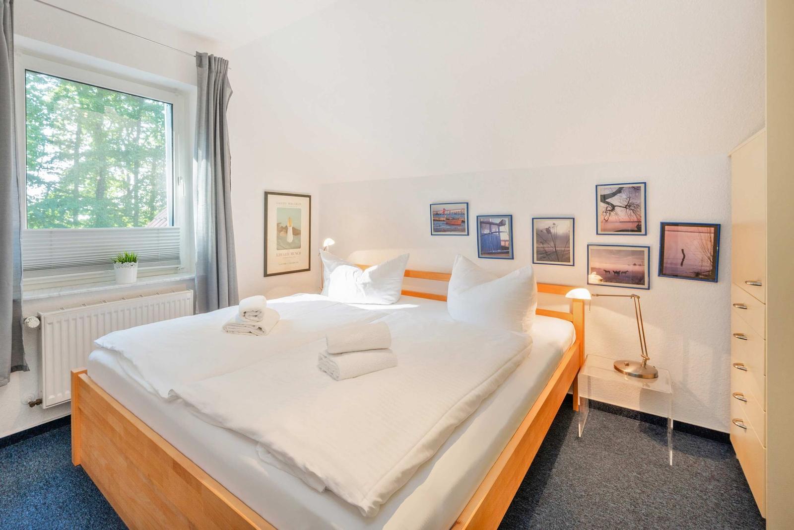Schlafzimmer mit Bett, Fenster und Wandbildern