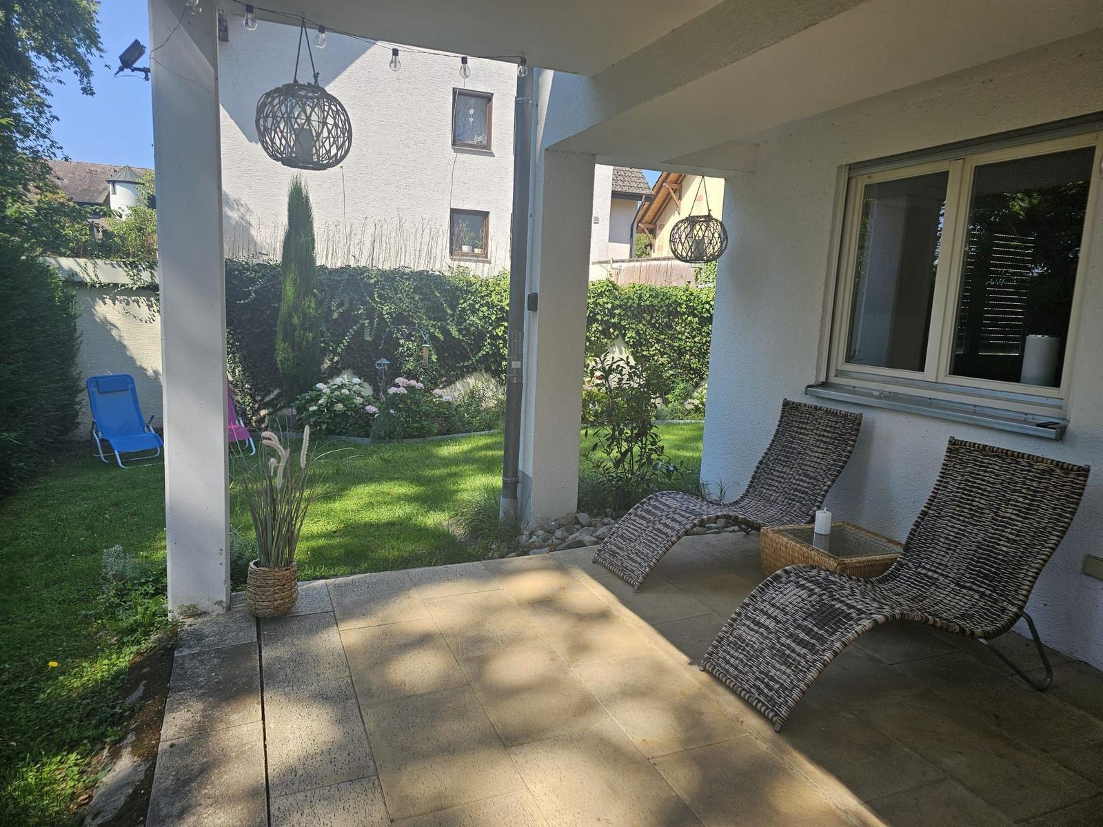 Terrasse mit zwei Liegestühlen und Garten im Hintergrund.